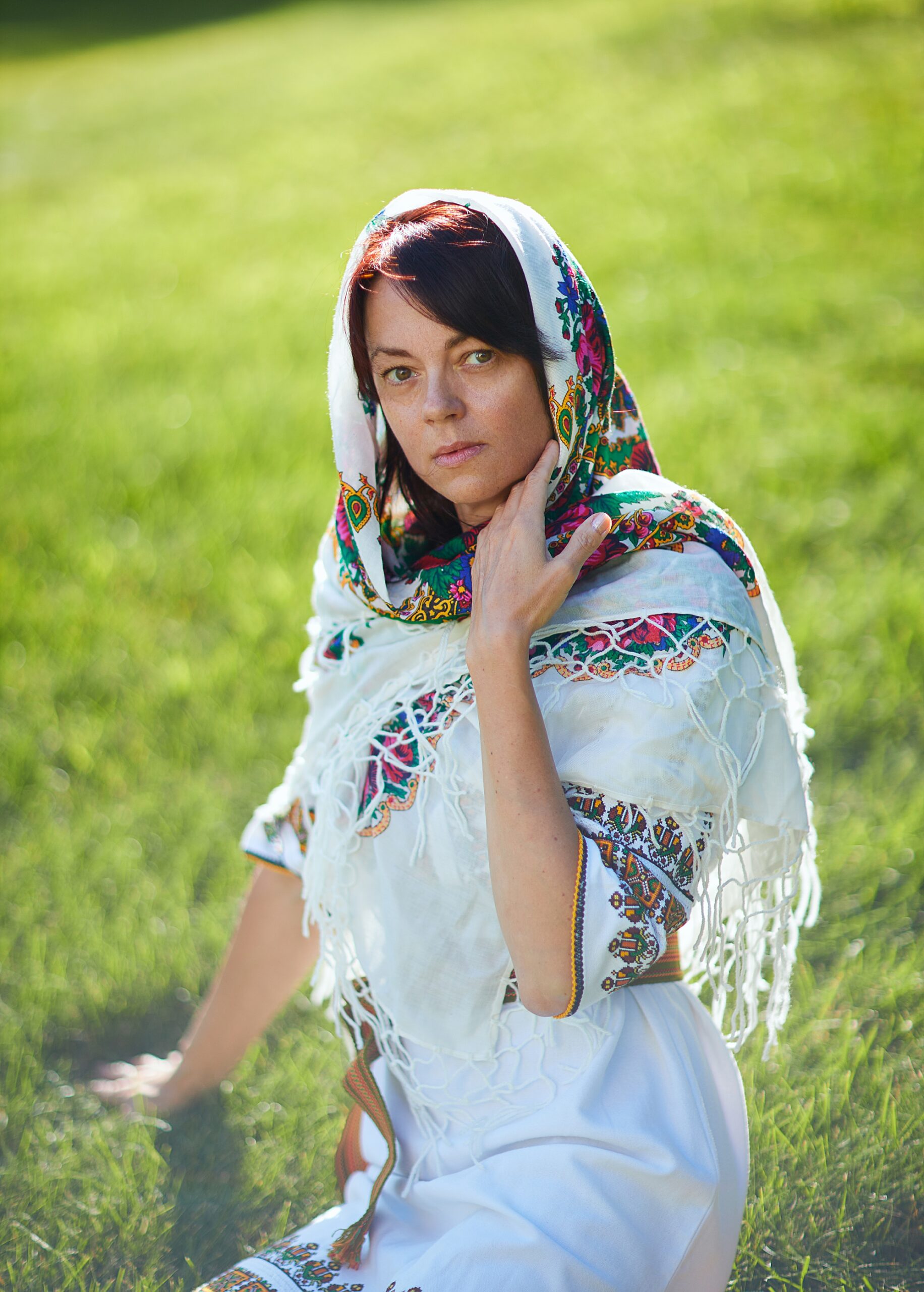 Ukrainian woman sitting on grass with head scarf 