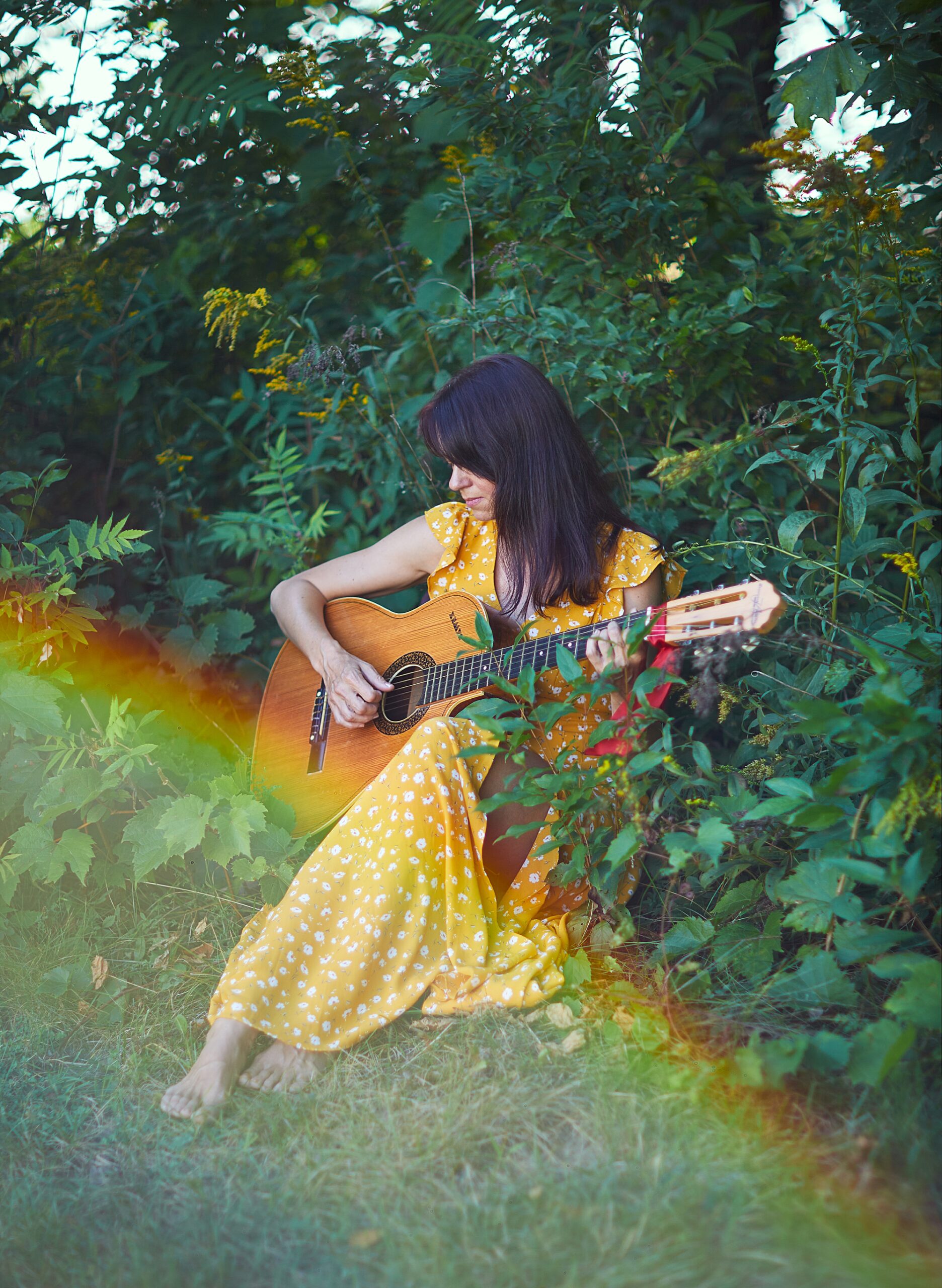 woman playing guitar in tall grass