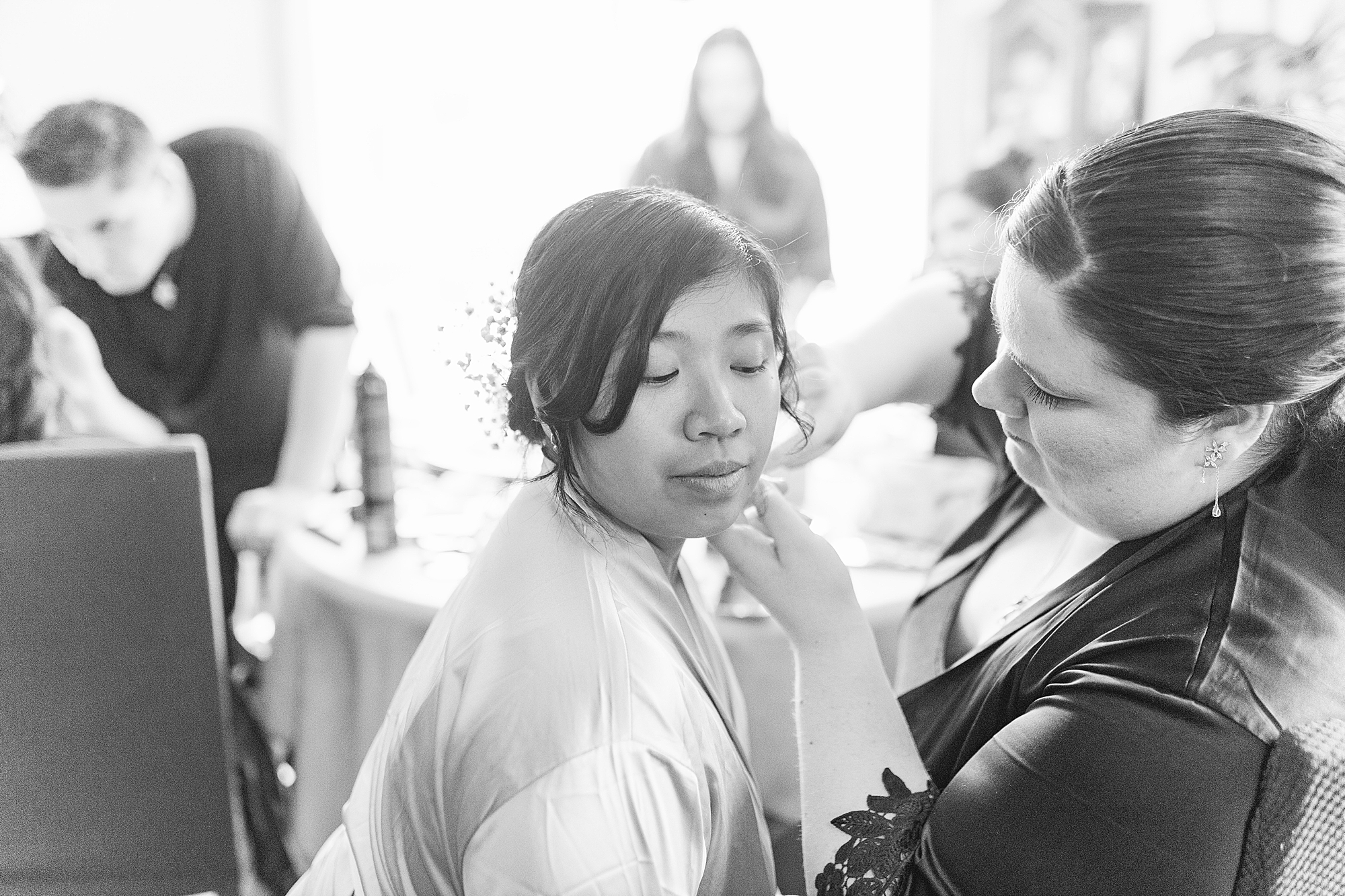 bridesmaid putting earring on bride while other bridesmaids are getting ready 