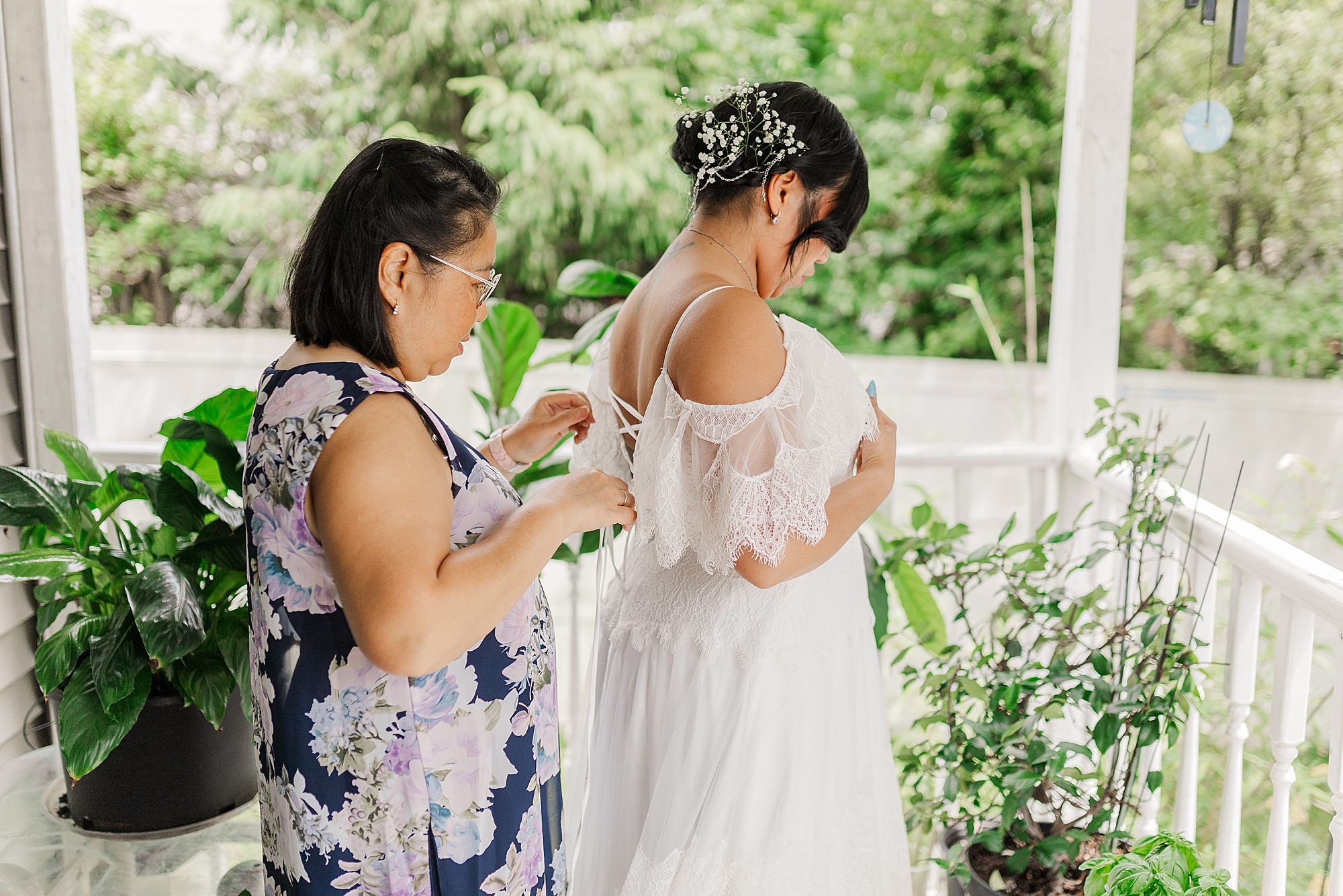 mother of bride tying up the back of brides dress 