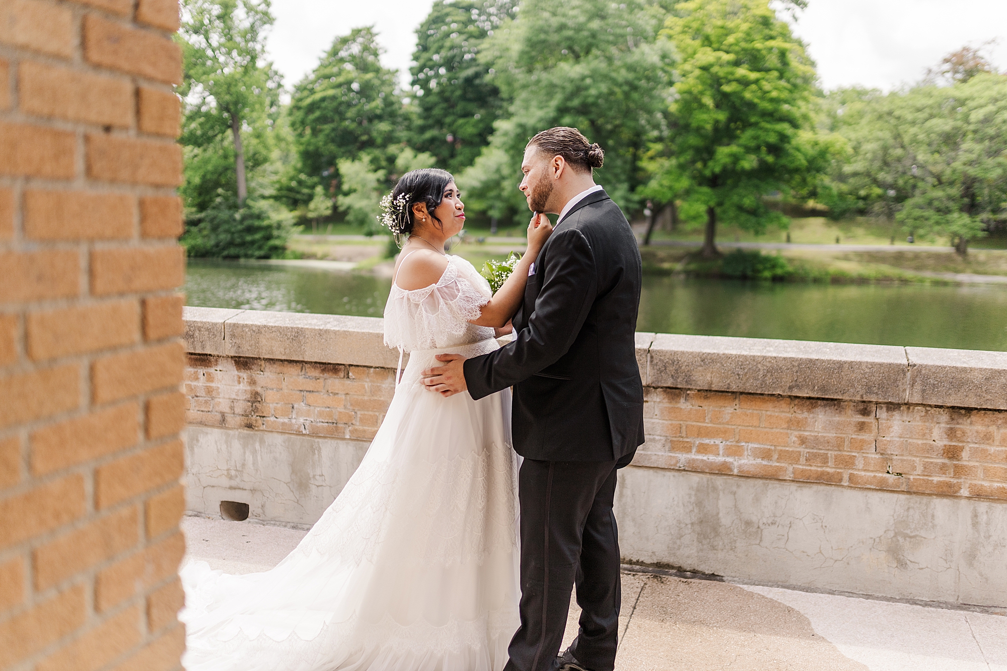 bride and groom seeing each other on a outdoor patio next to a lake 