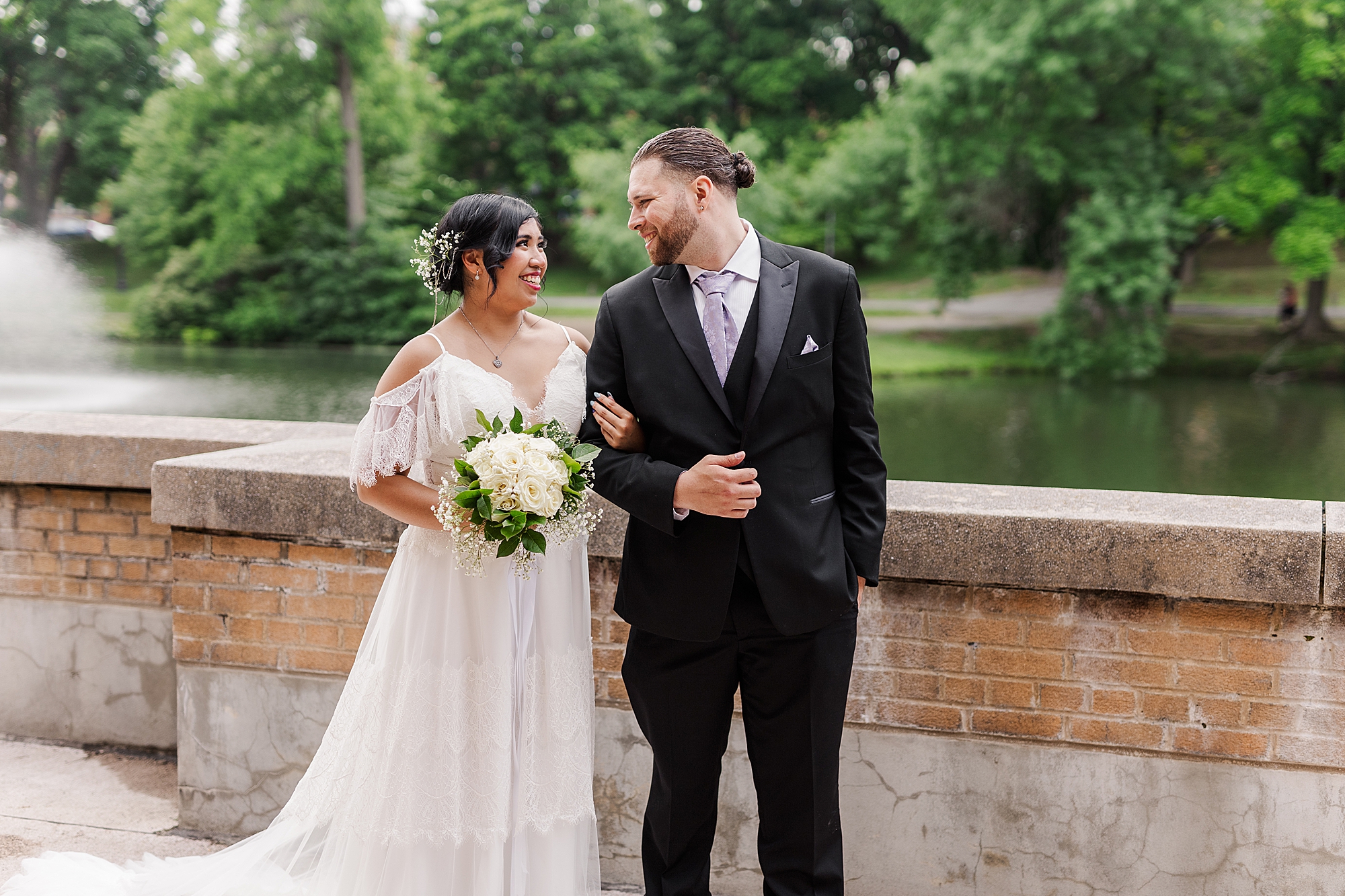 bride holding onto grooms arm while holding bouquet 