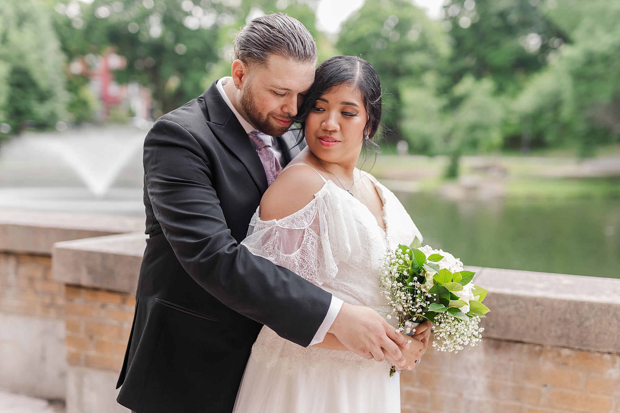 bride and groom holding each other near lake 