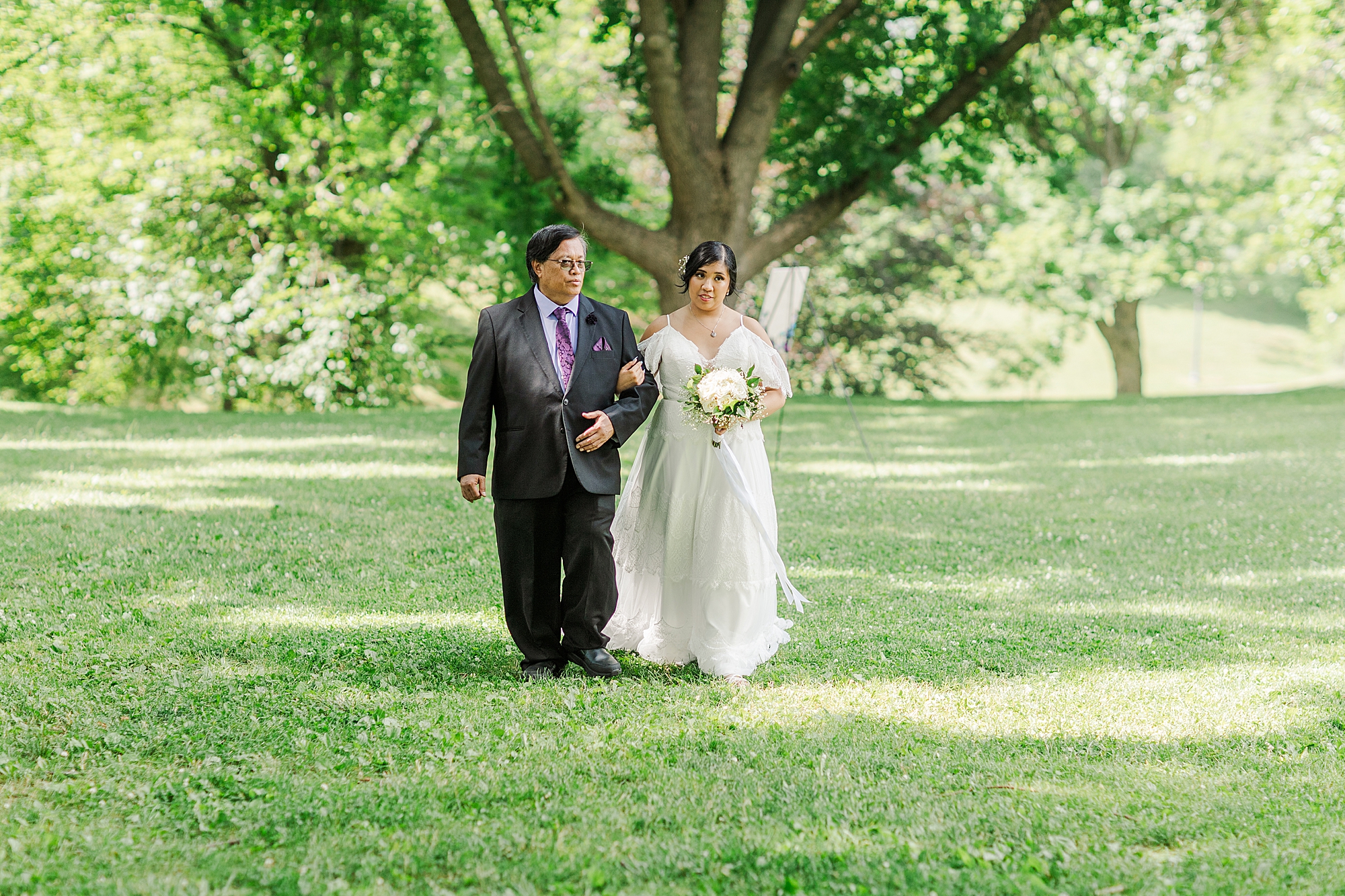 bride walking with father down the aisle holding bouquet 