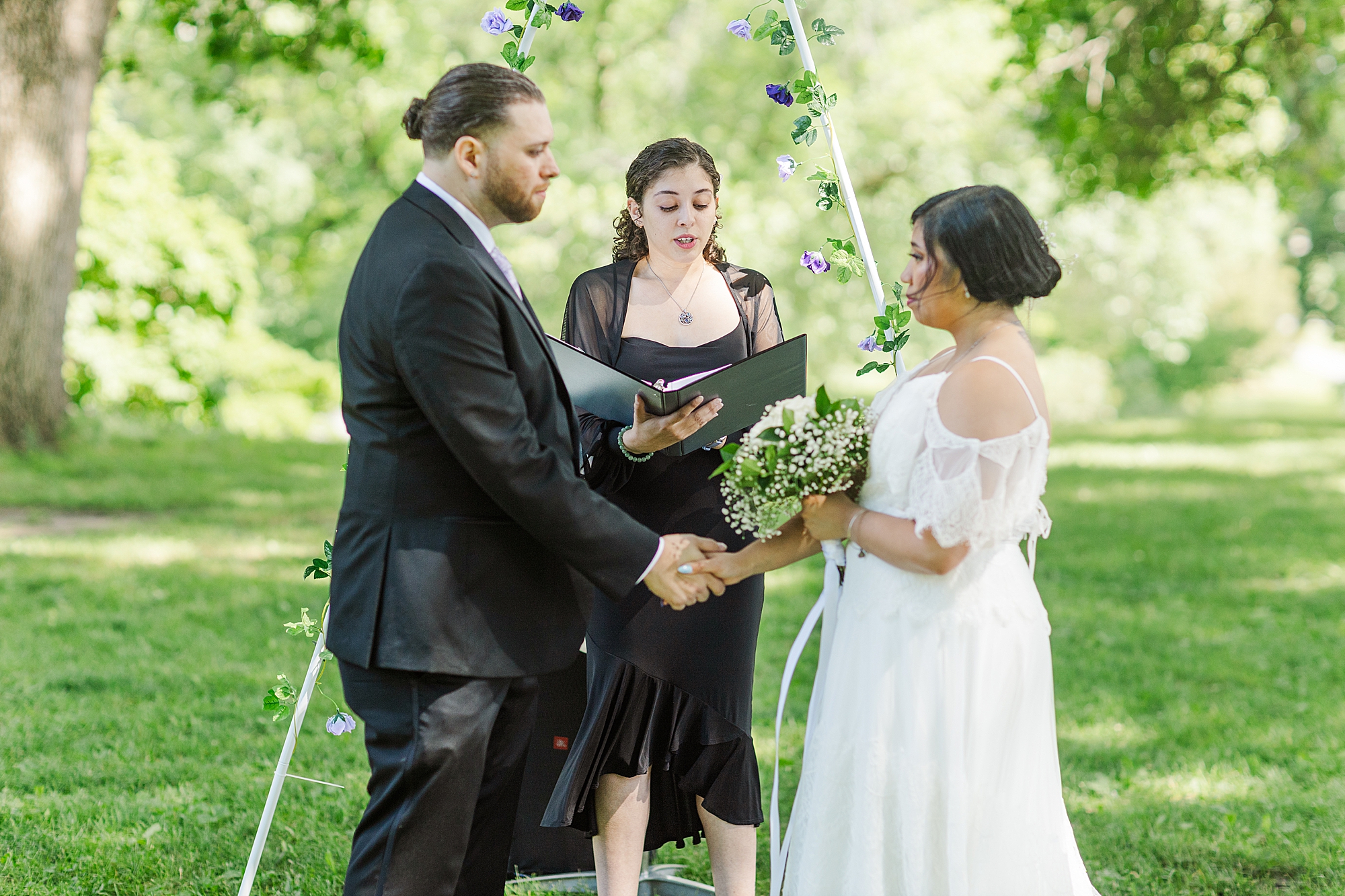 bride and groom holding hands and standing in front of wedding arch