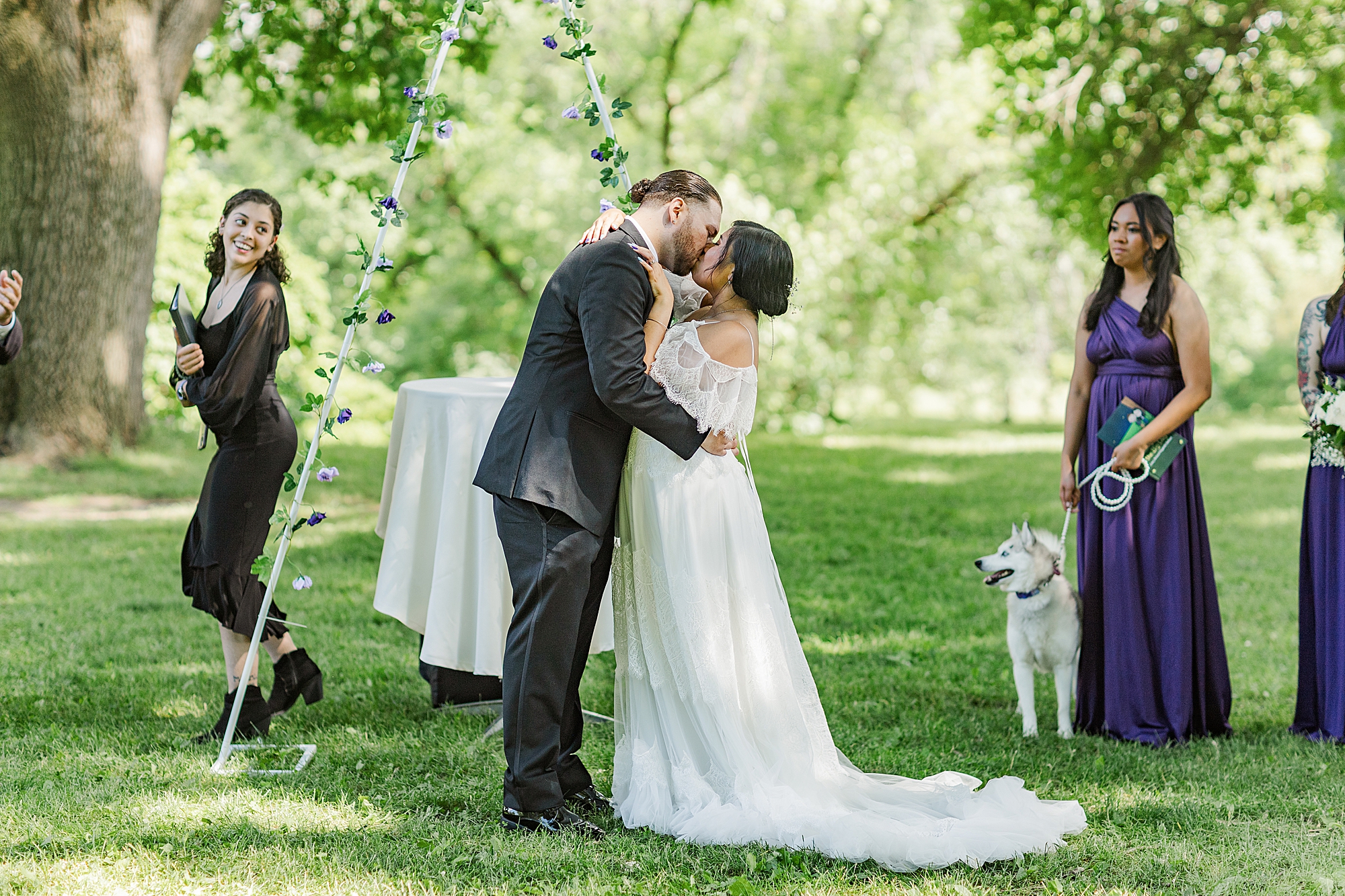 bride and groom sharing first kiss and married couple in front of wedding arch 