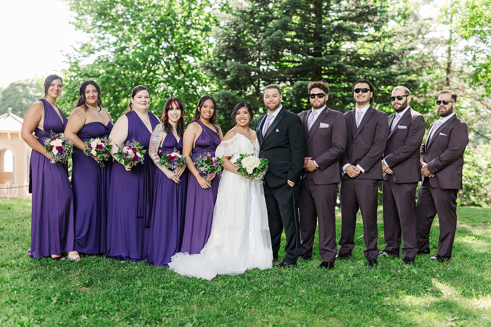 bridal party with bridesmaids and groomsmen with flowers in park 