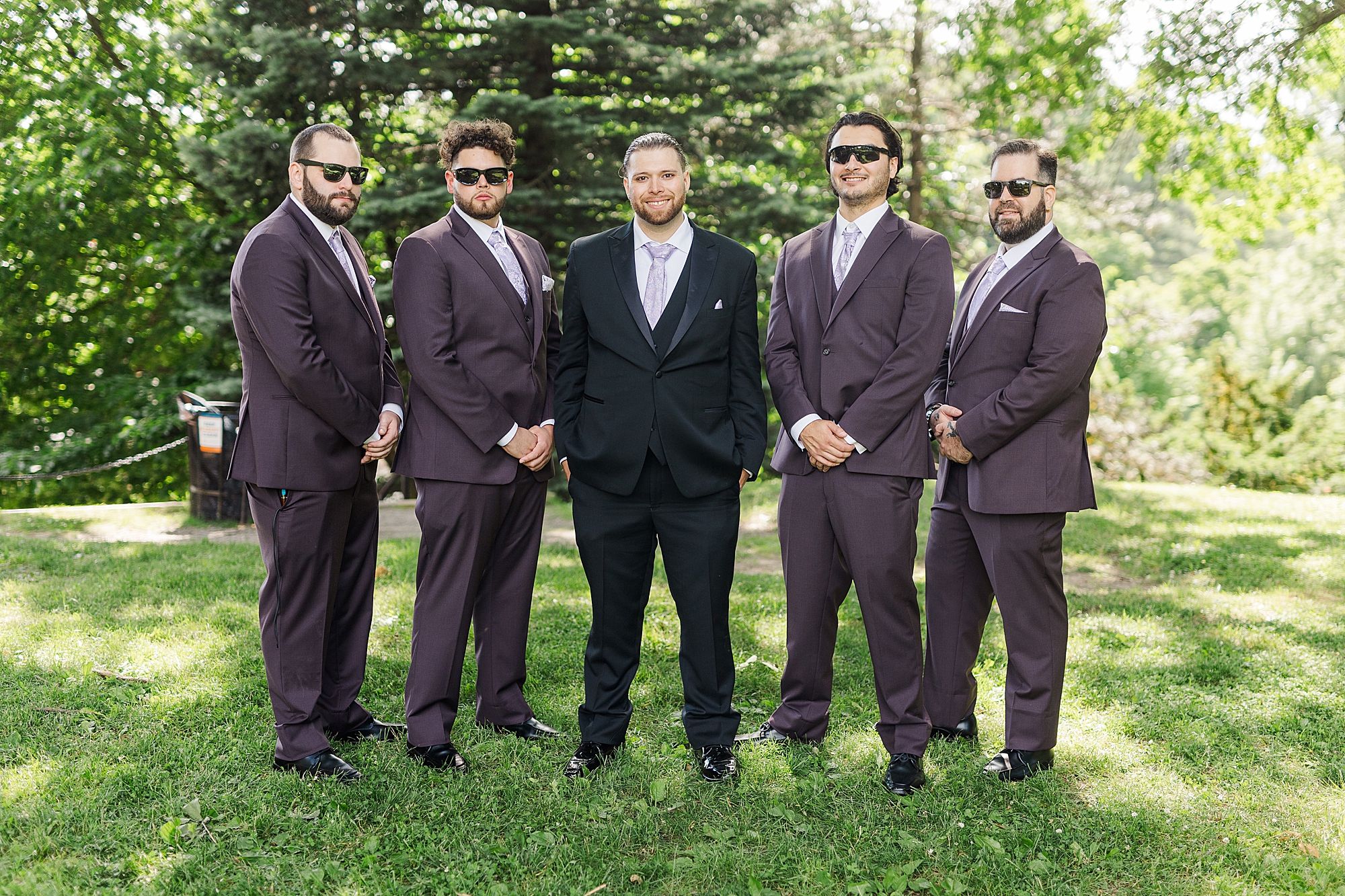 groomsmen in park with greenery and trees 