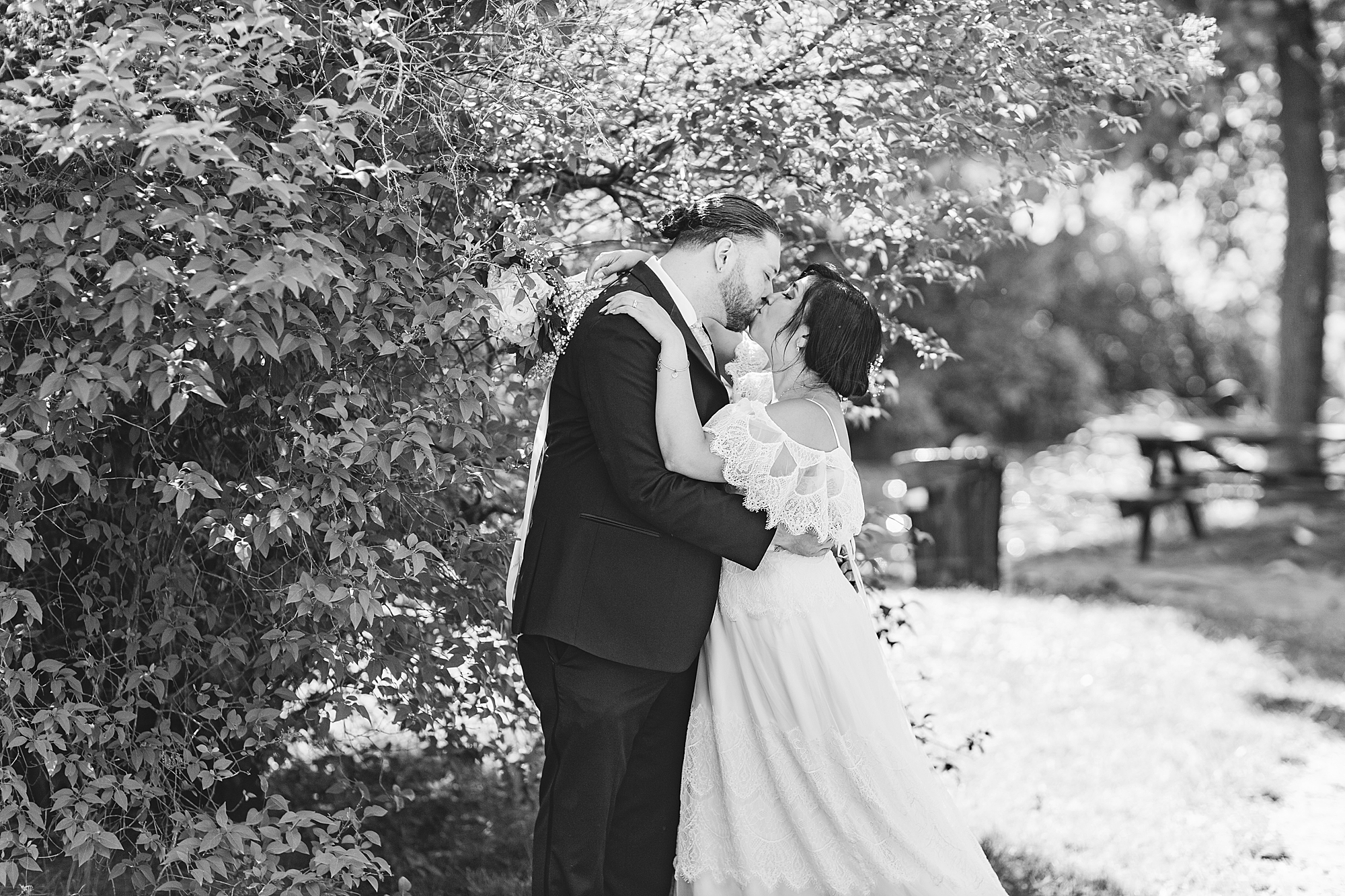 bride and groom kissing underneath a tree 