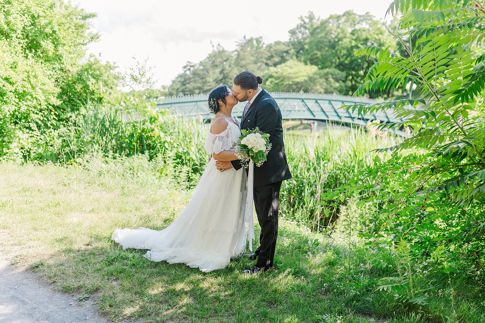 bride and from share a kiss standing next to a bridge 