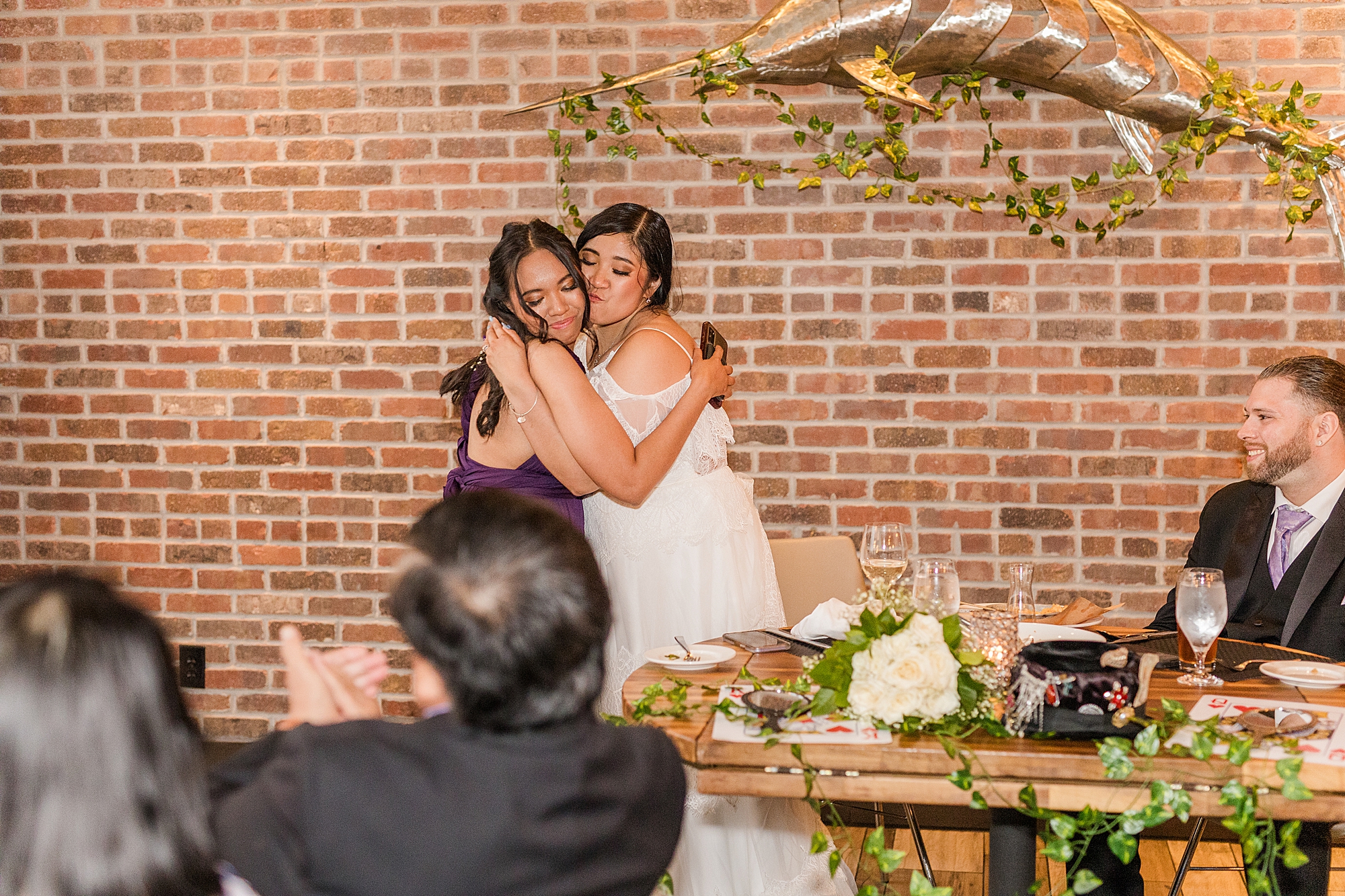 sister of the bride hugs her sister at dinner 