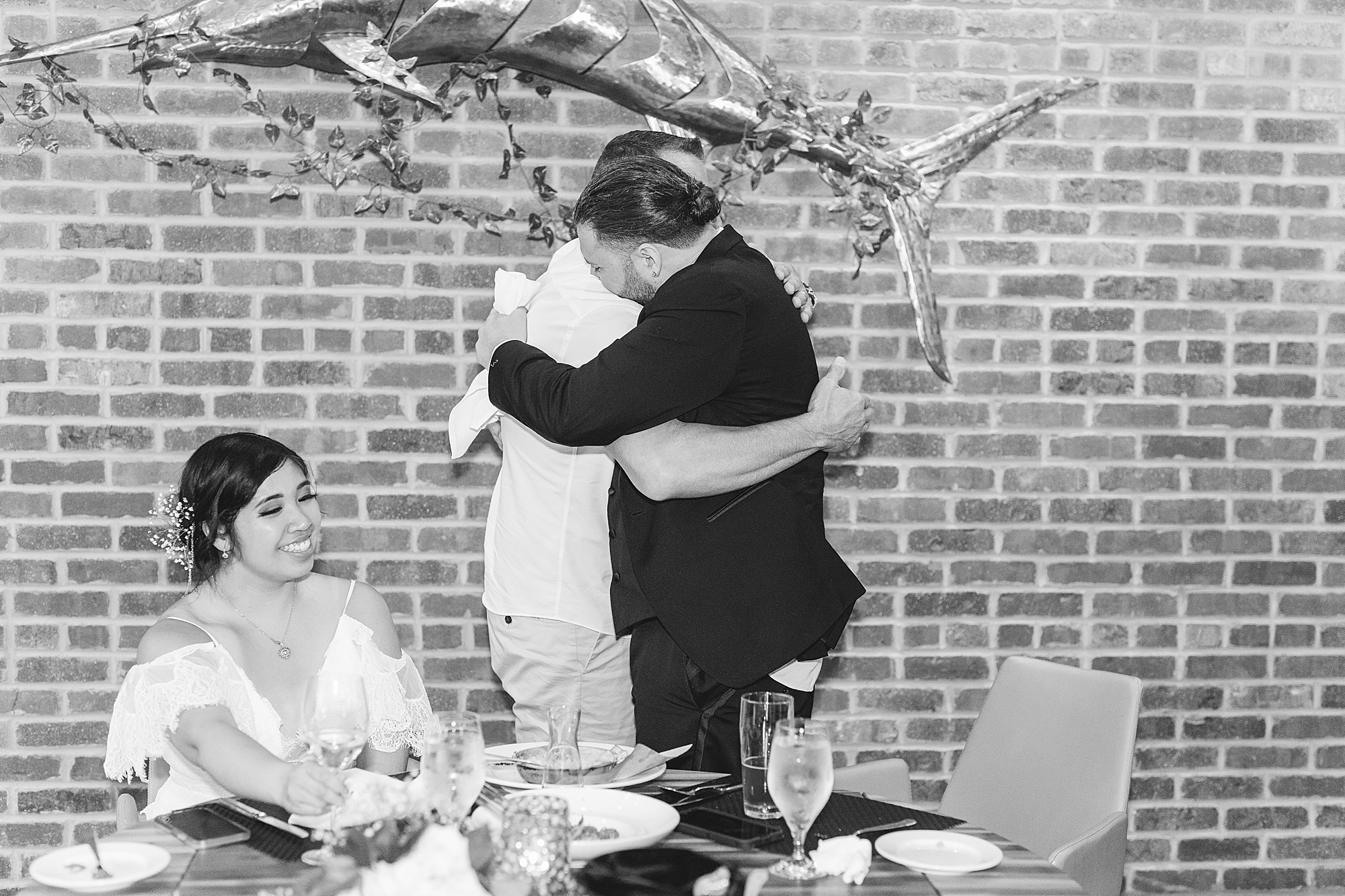 father of the groom hugs his son at dinner 