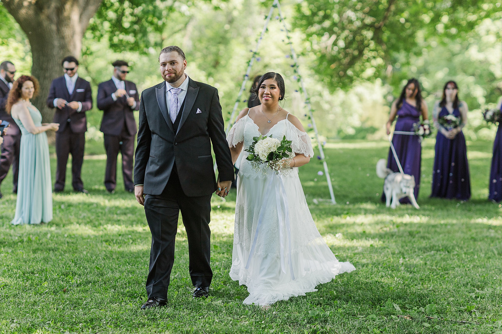 bride and groom walking down aisle while bride is holding bouquet of flowers 