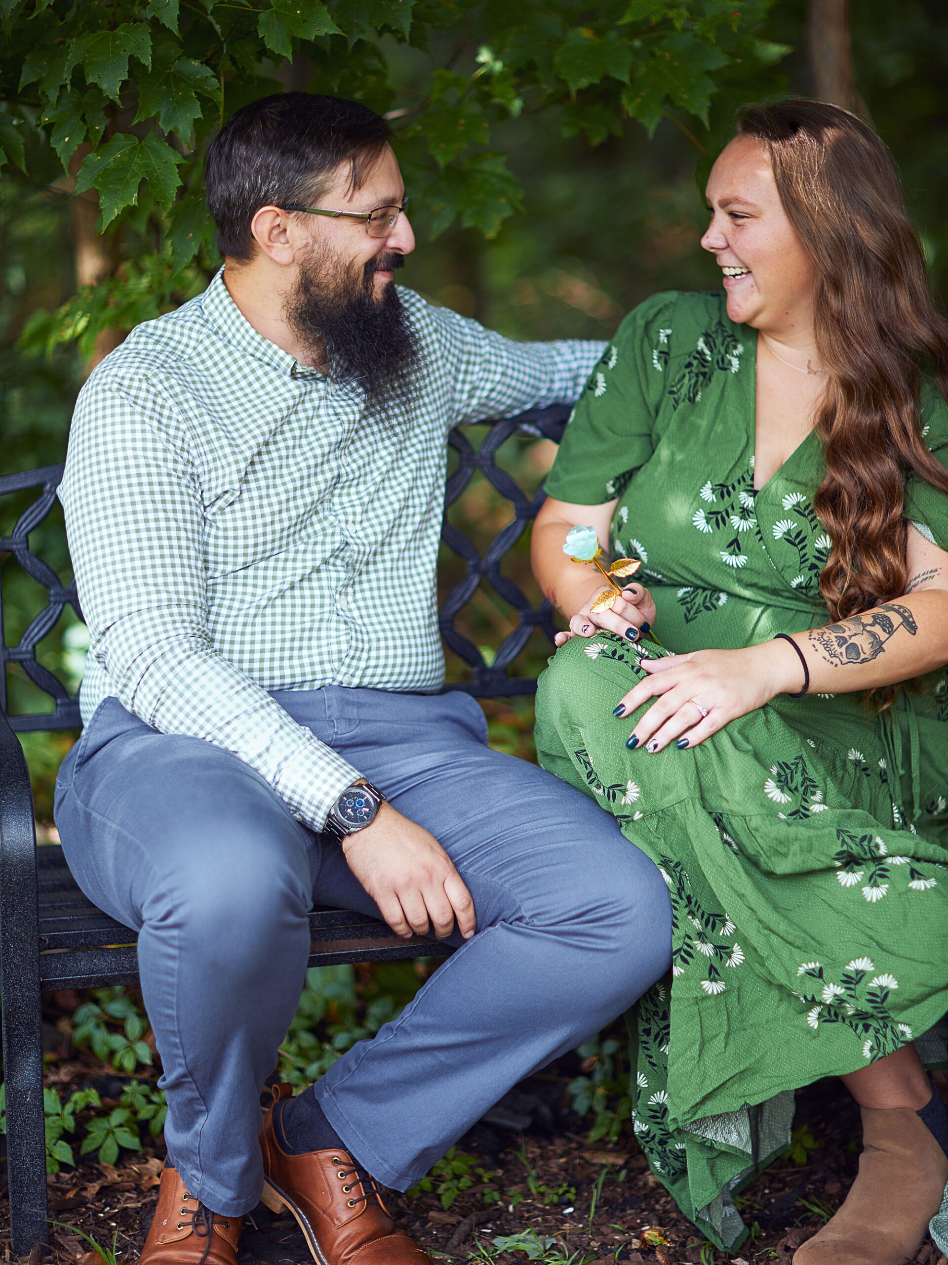 couple laughing with each other sitting on a bench