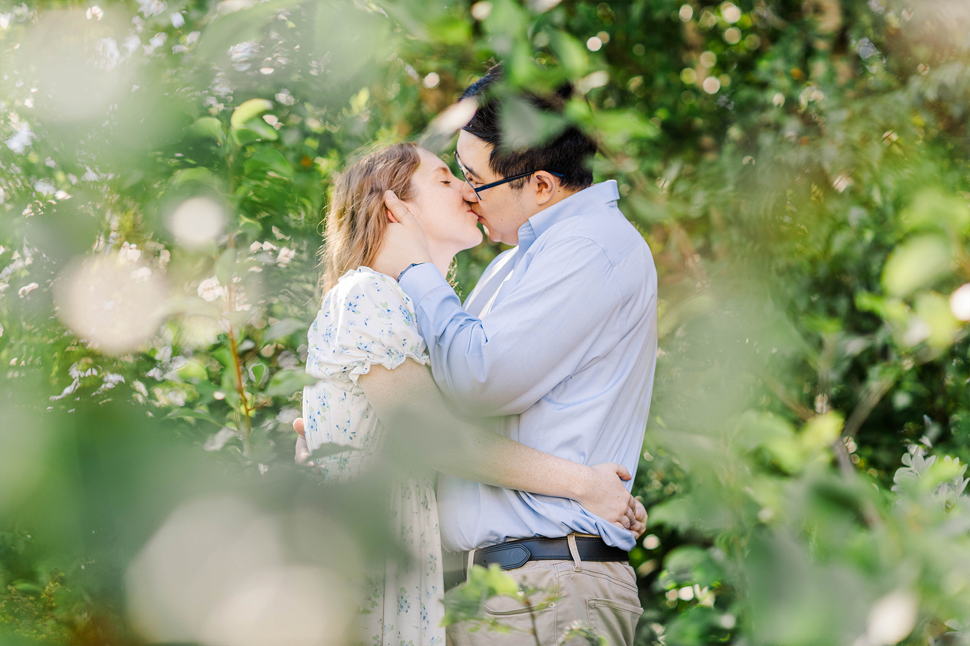 couple sharing a kiss in tall greenery 