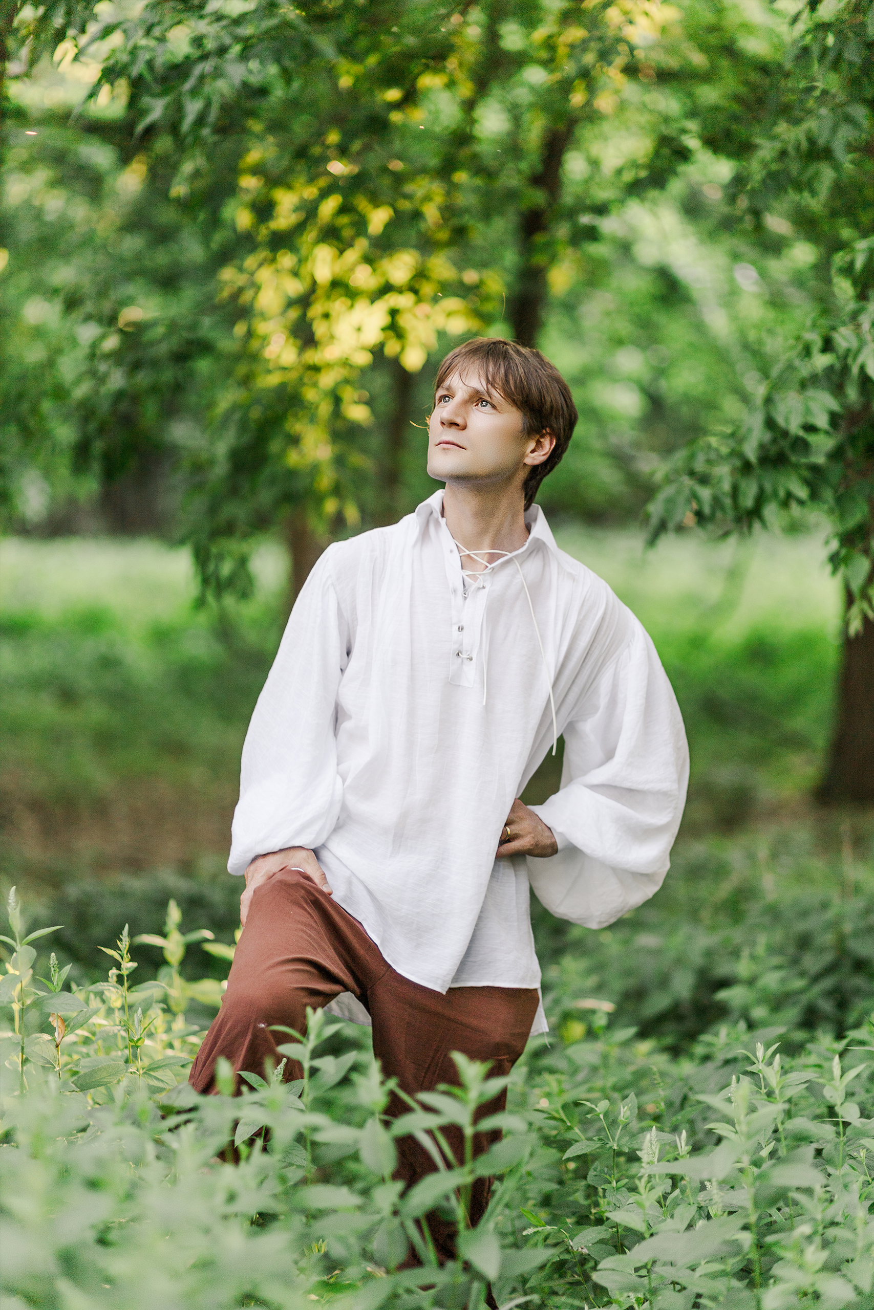 man in oversized shirt standing in tall grass