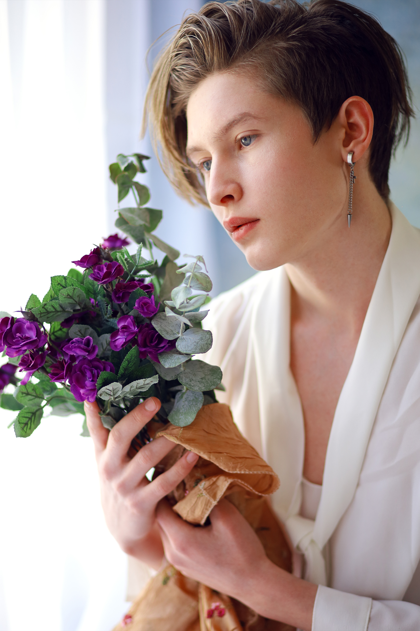 young man with white shirt earrings and flowers