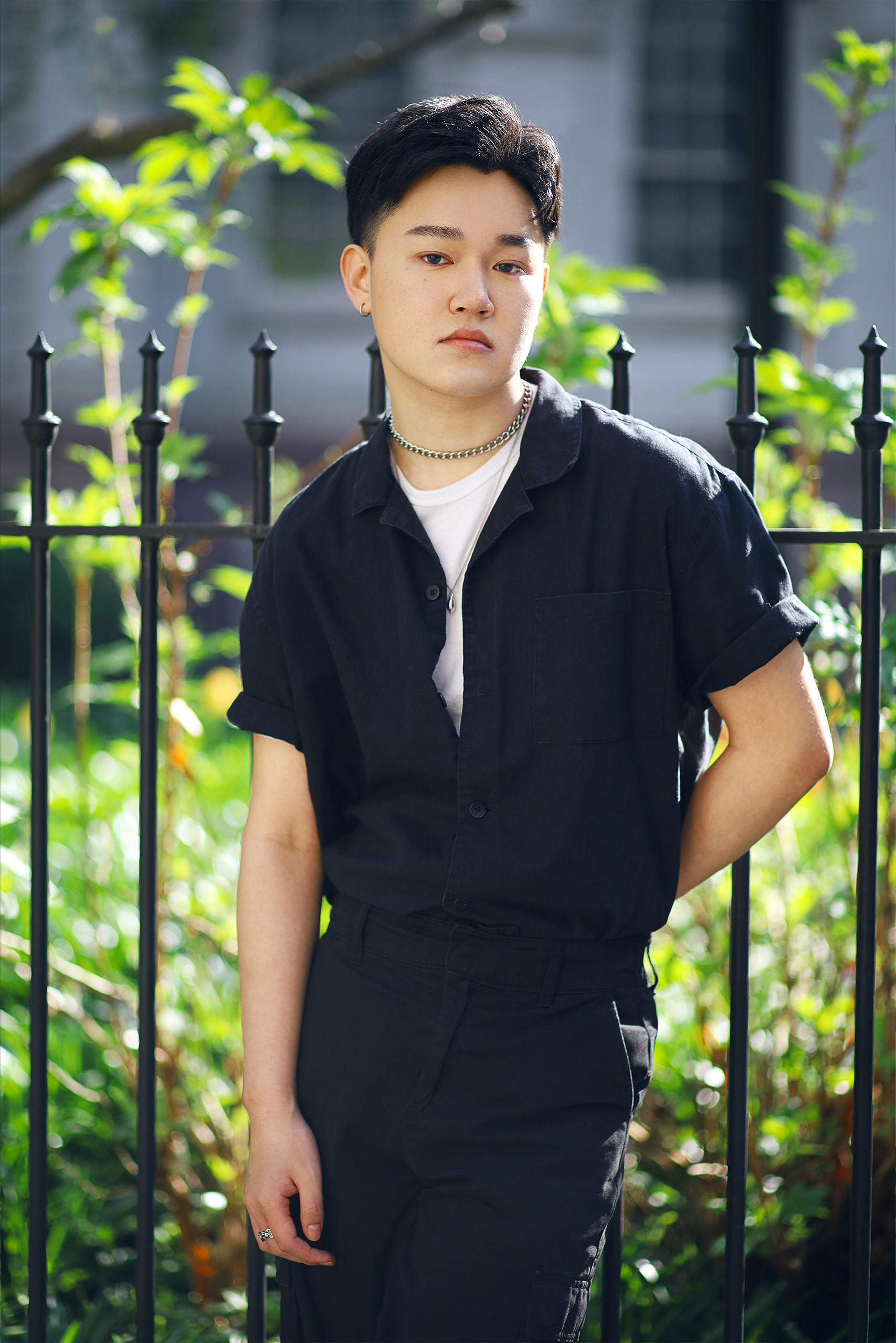model posing on iron fence with greenery and backlighting