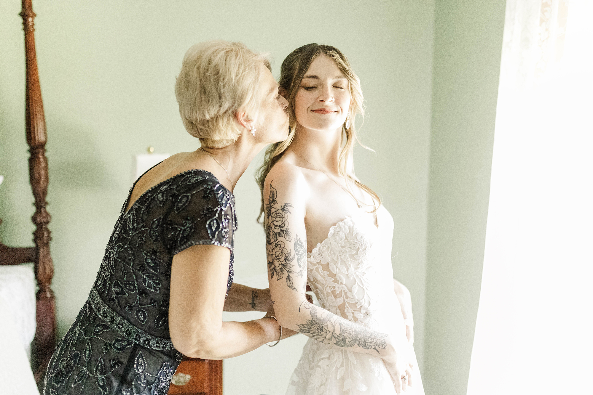 mom giving daughter a kiss in wedding dress