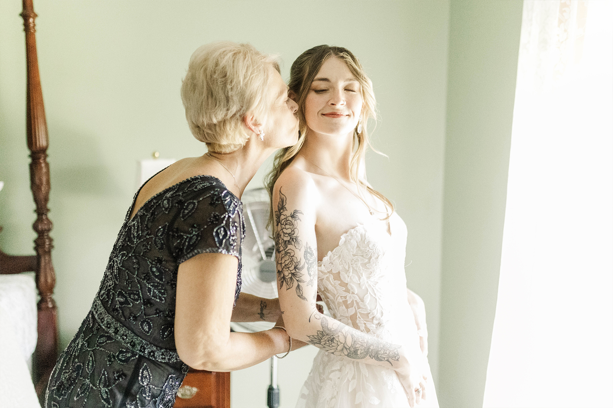 mom giving daughter a kiss in wedding dress
