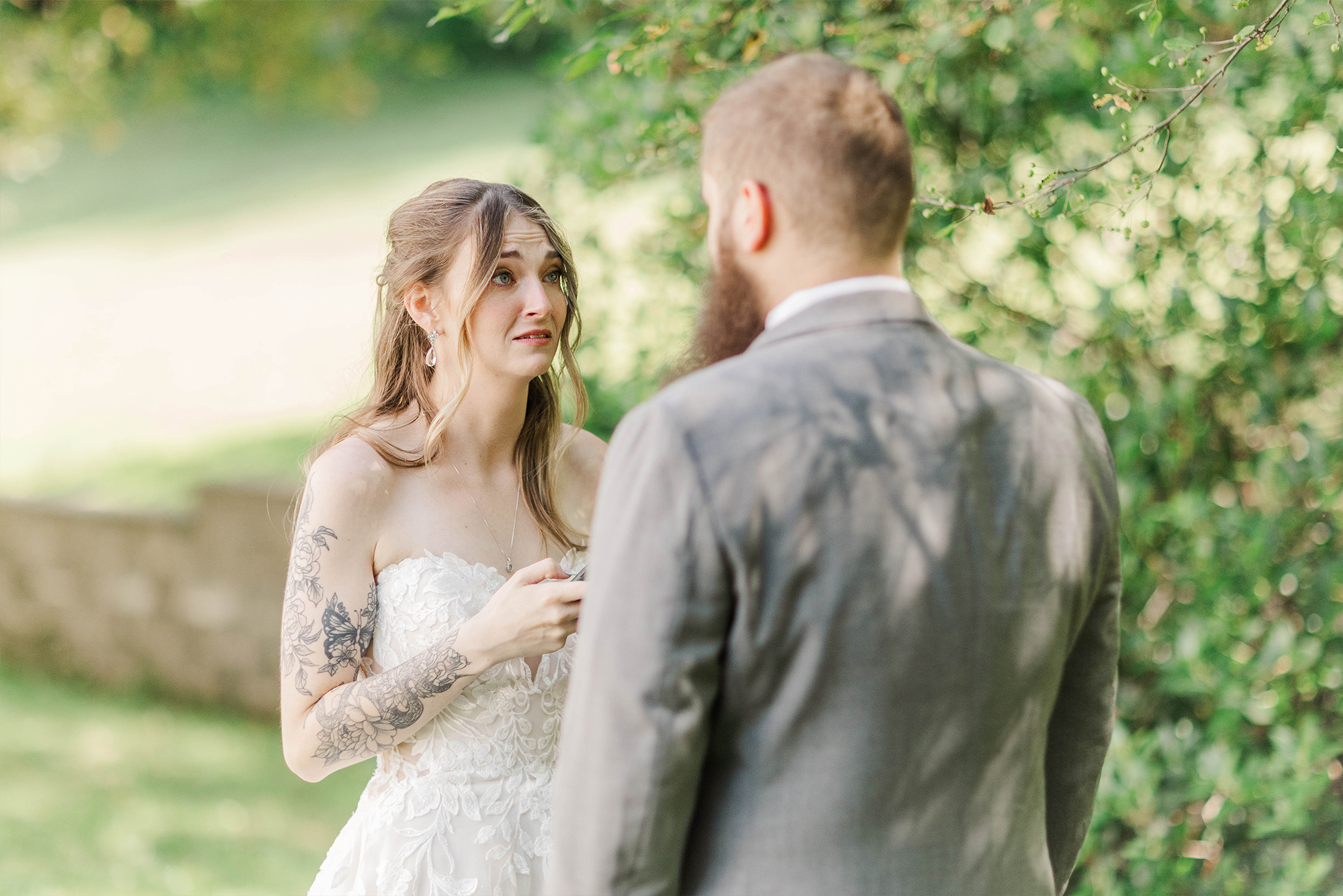 bride looking at groom next to greenery