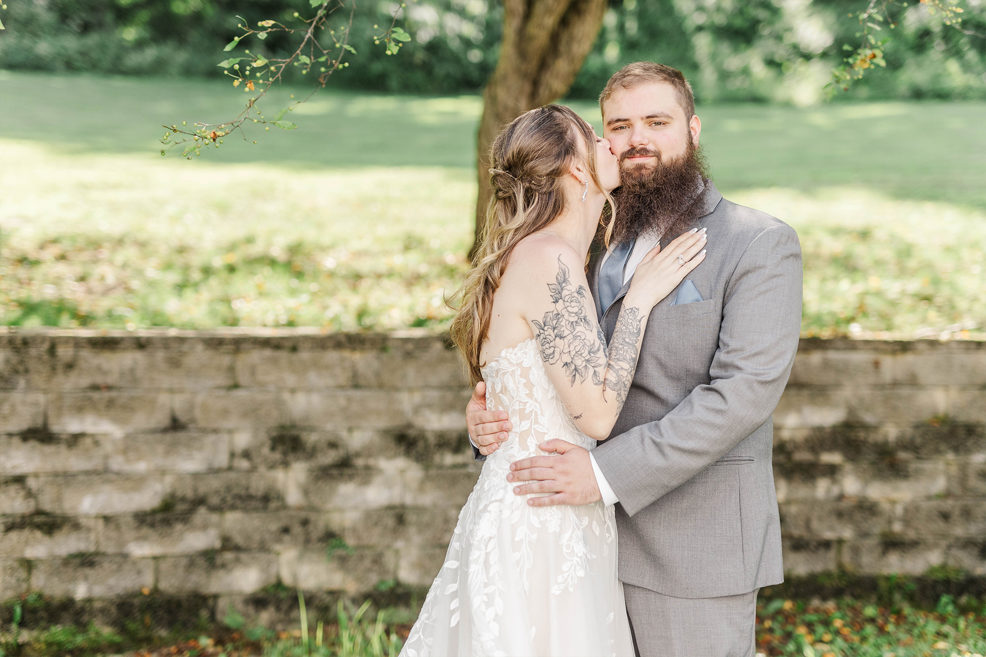 bride kissing groom under tree