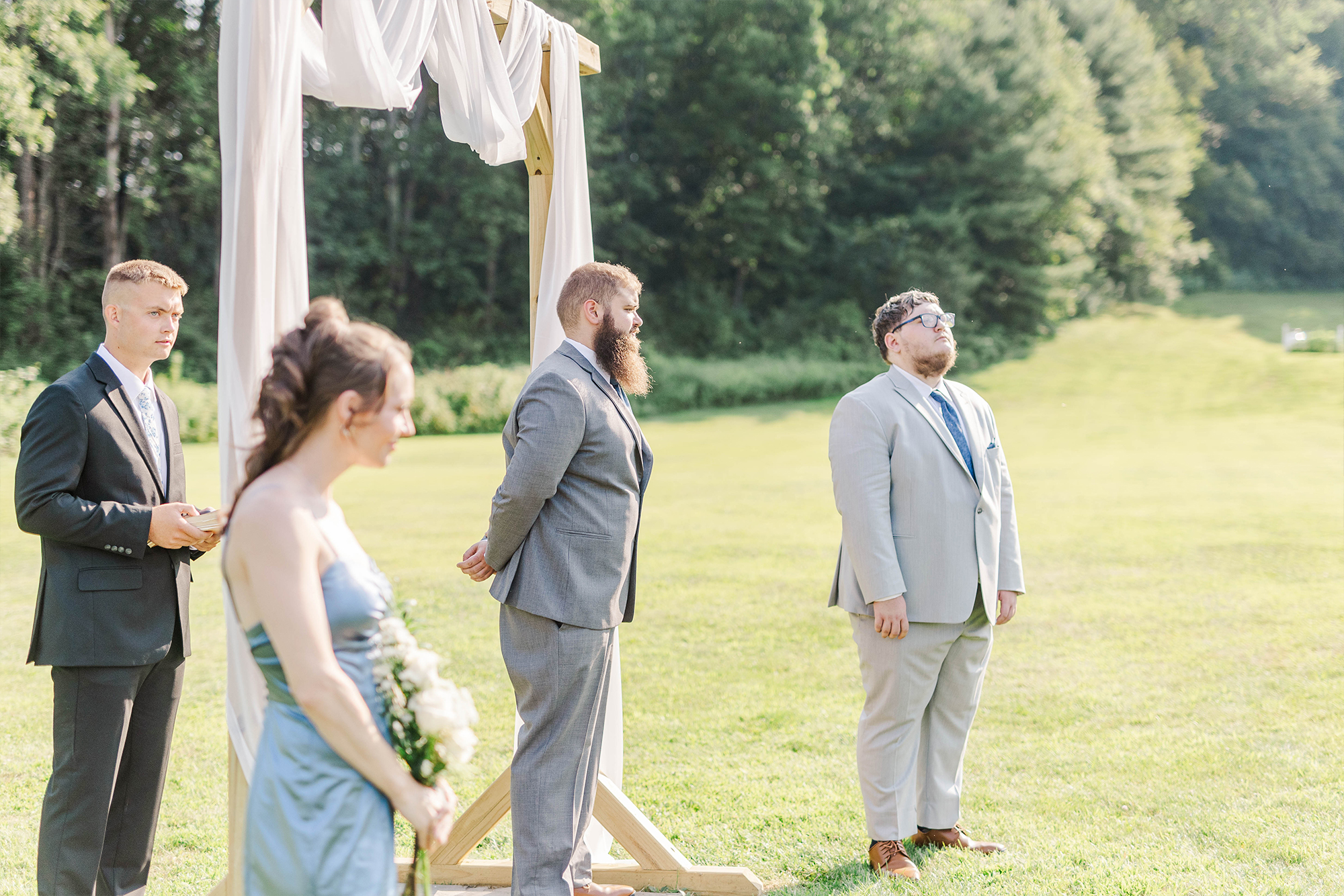 wedding party and officiant standing under arch