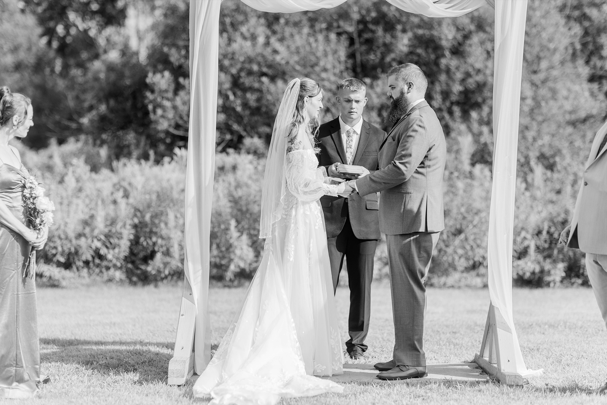 bride and groom exchanging rings under wedding arch