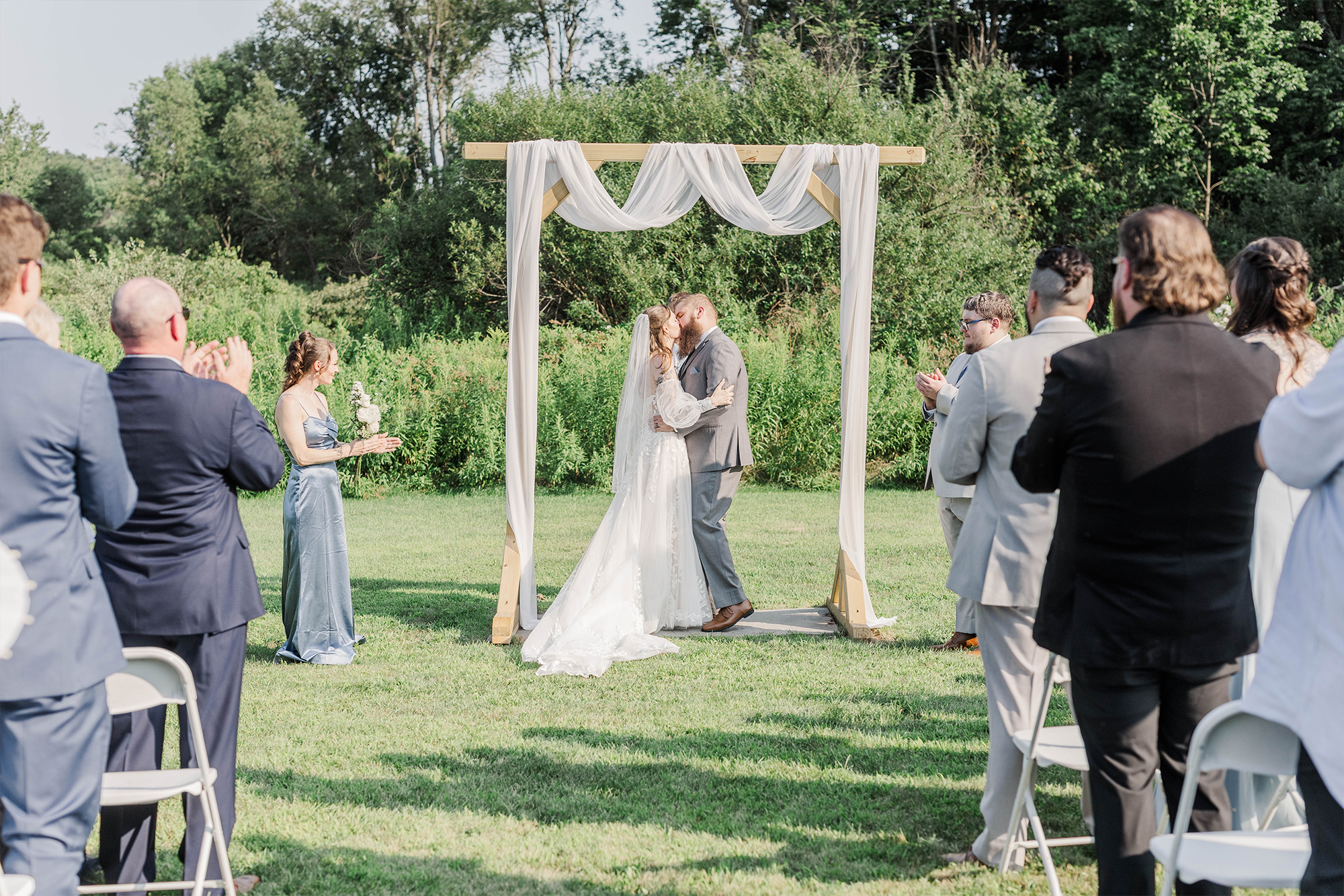 bride and groom sharing first kiss as guests clap