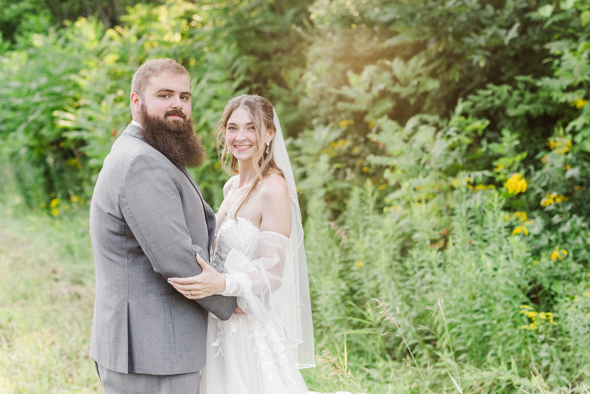 bride and groom standing in greenery