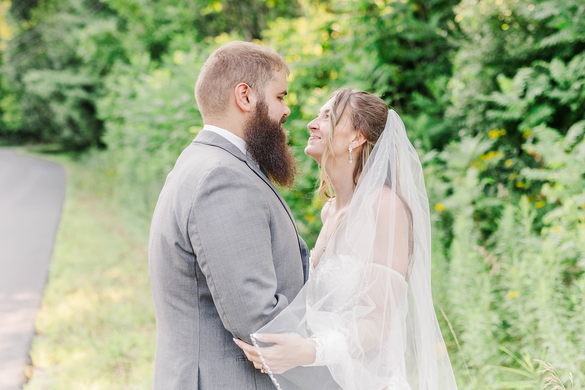 bride and groom holding each other in greenery