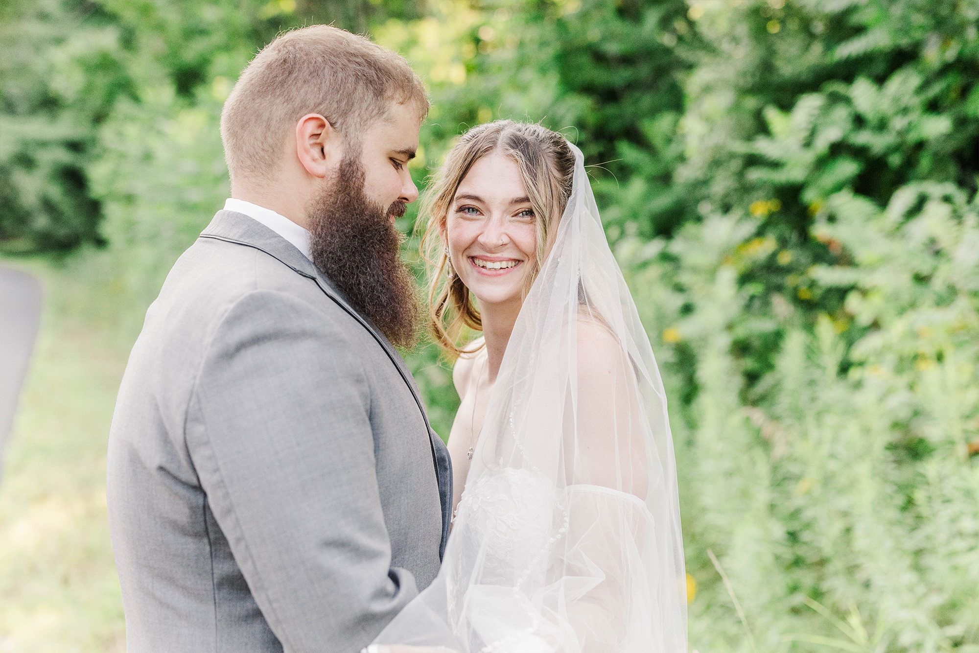 bride smiling at camera while holding husband