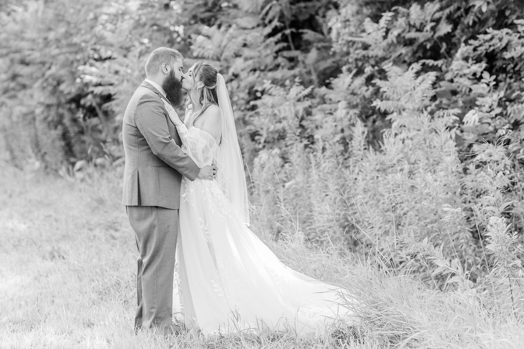 bride and groom sharing kiss in field
