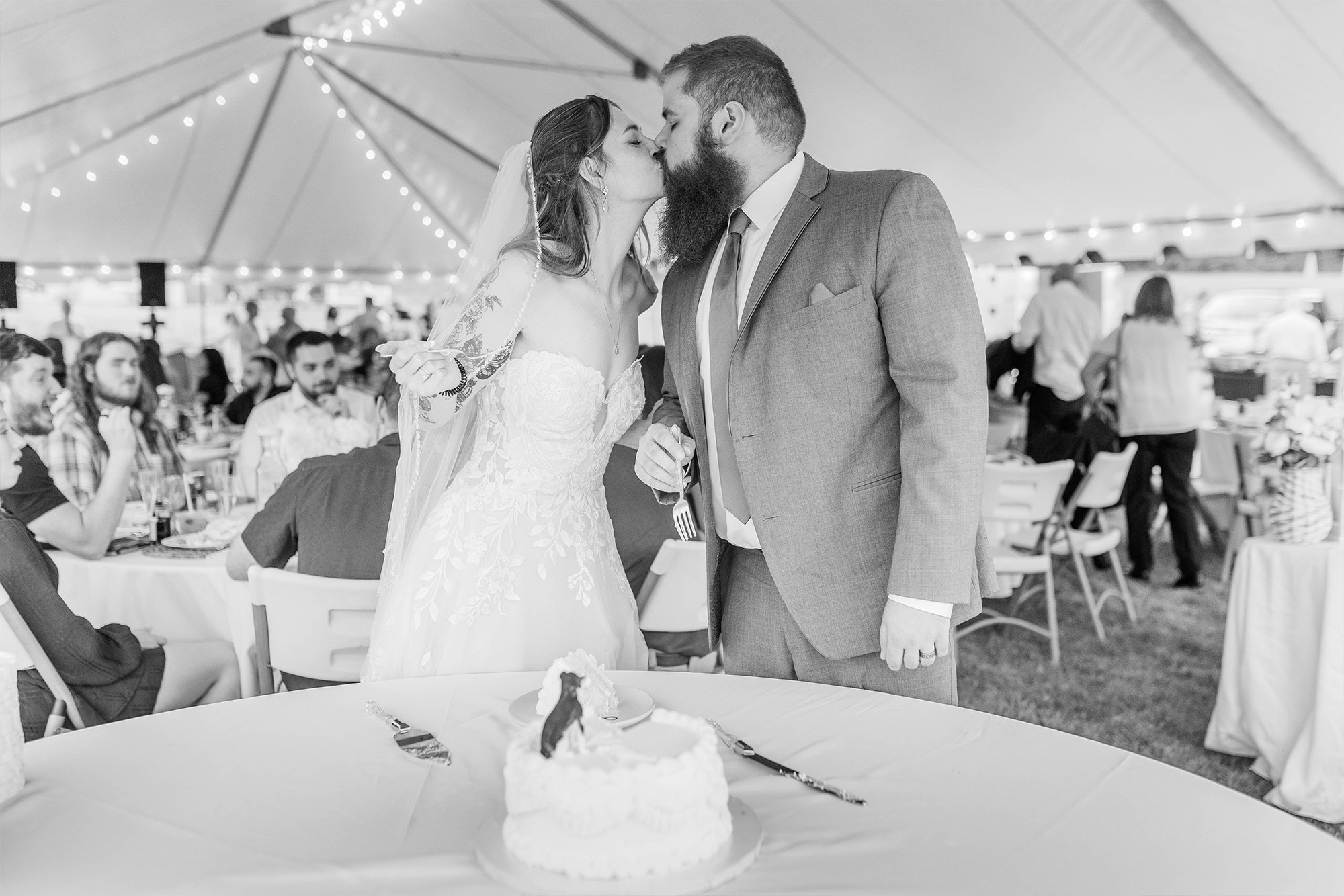 bride and groom sharing kiss with cake and reception