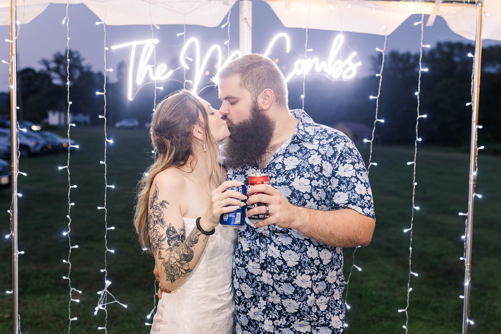 bride and groom sharing kiss under neon sign with drinks
