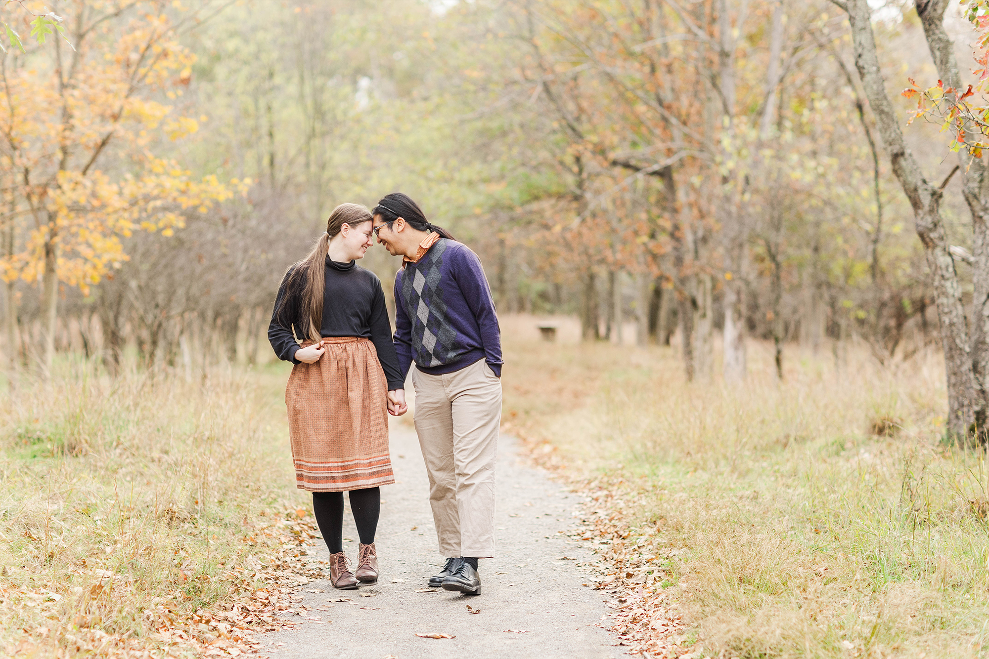 couple walks hand in hand in park