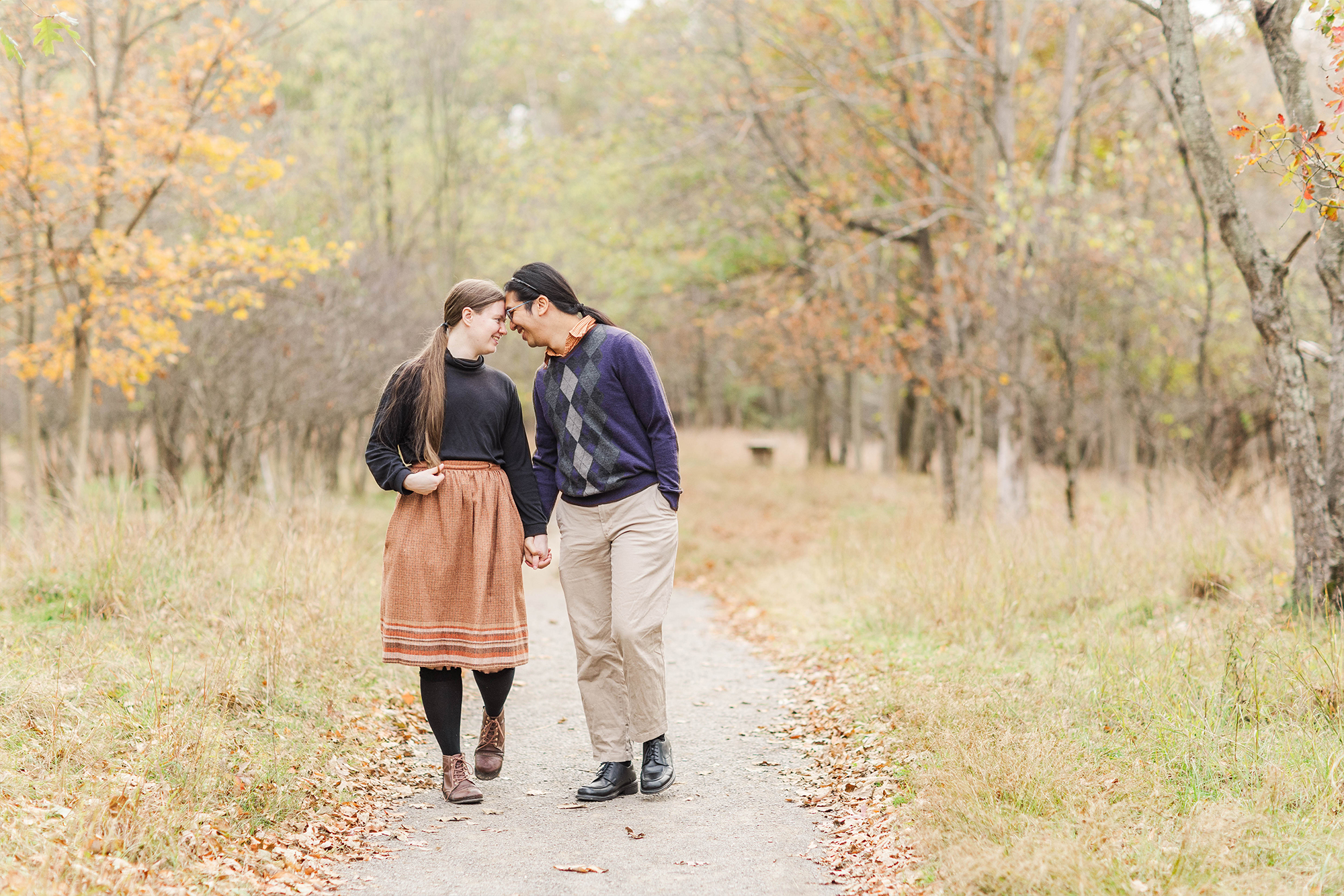 couple walking on trail holding hands with foreheads touching