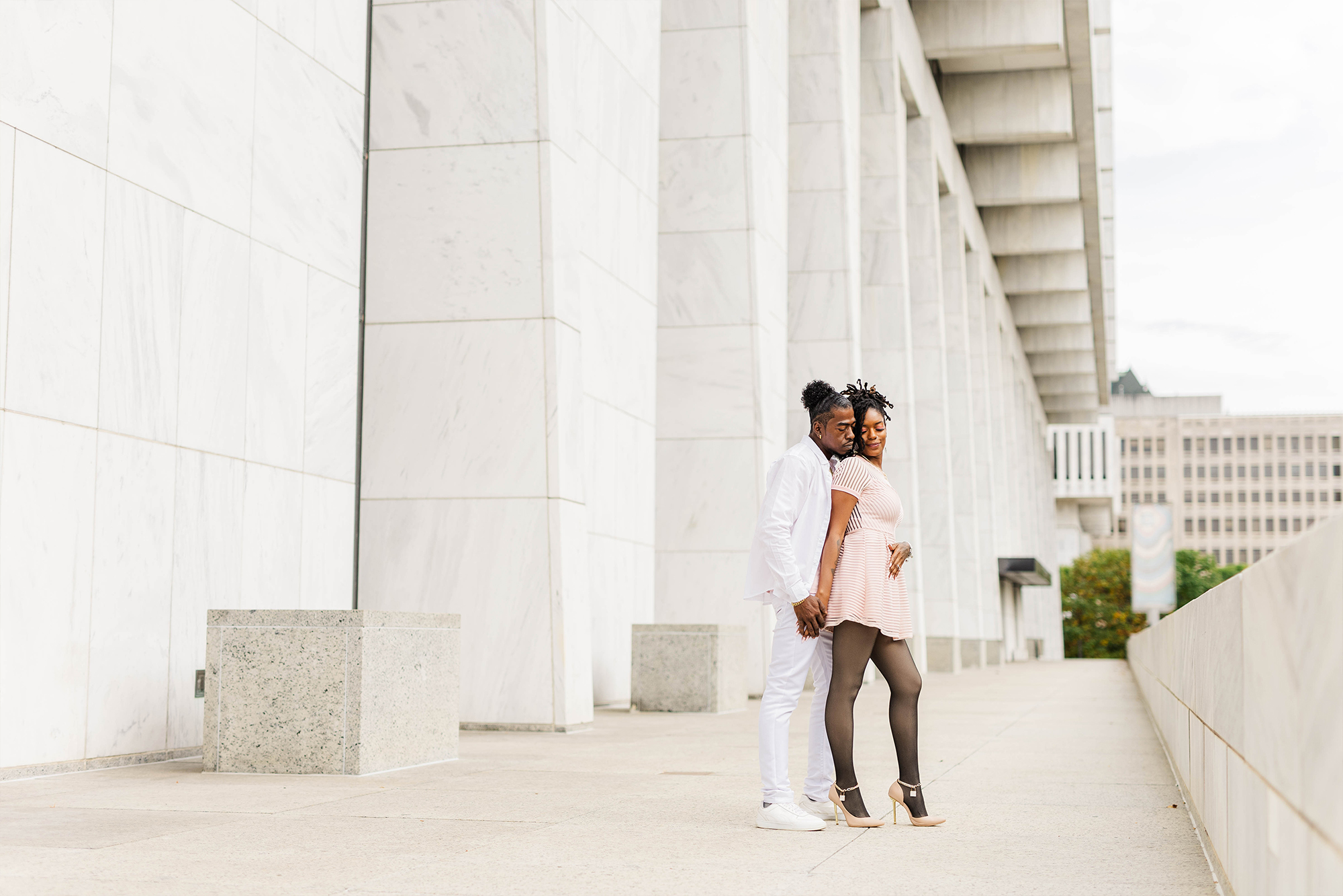 couple posing with each other in front of architectural office building