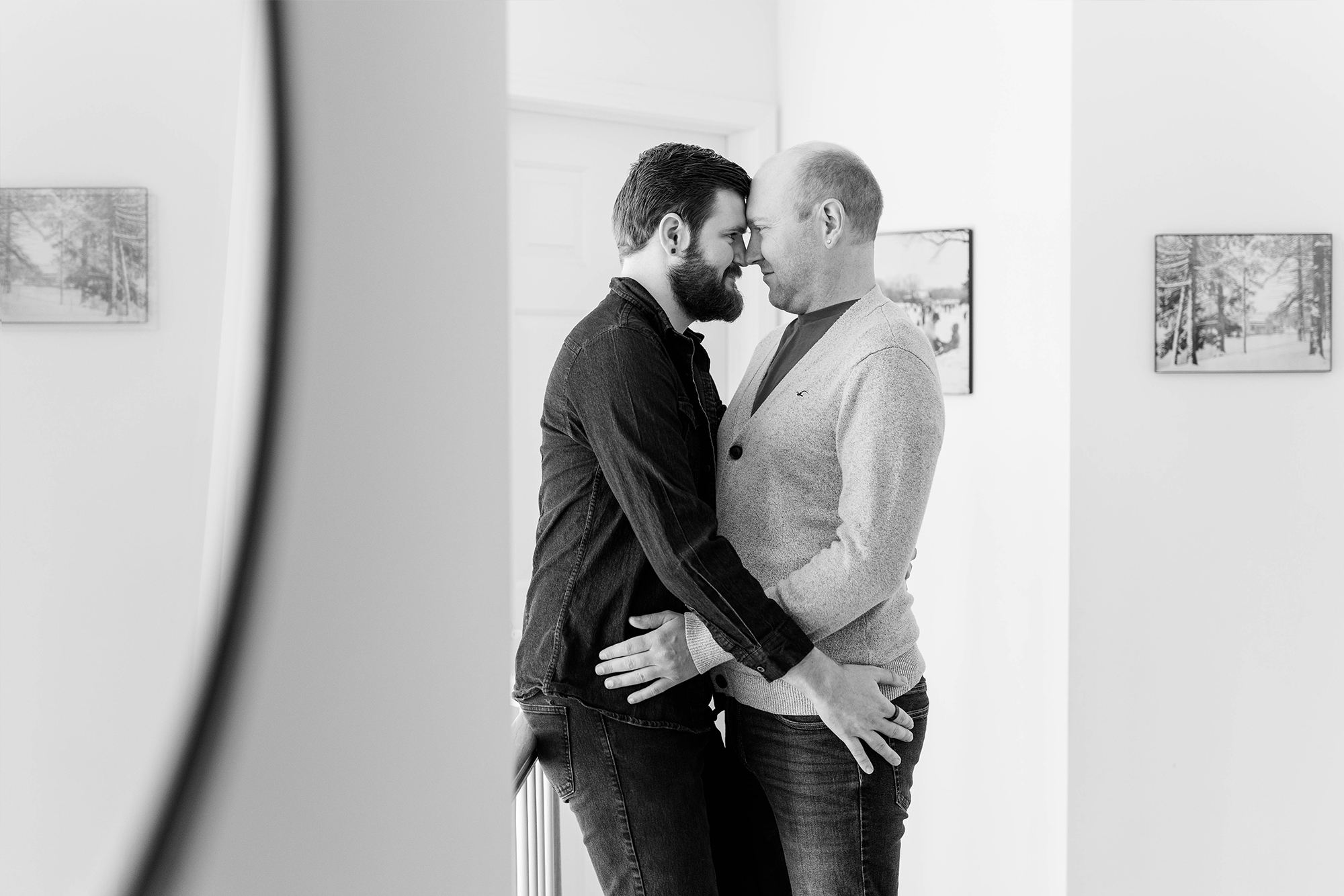 couple leaning against railing while resting their heads against each other