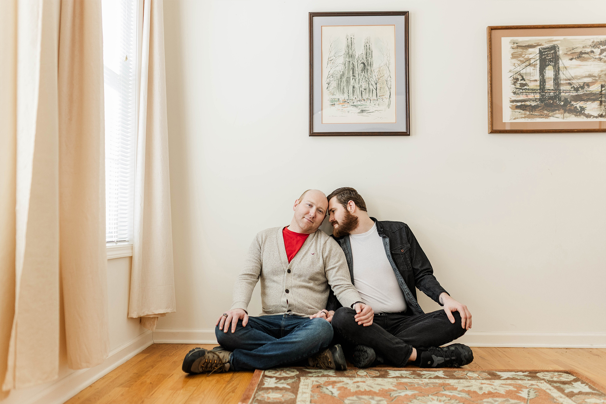 man rests his head on partners temple while sitting on living room floor