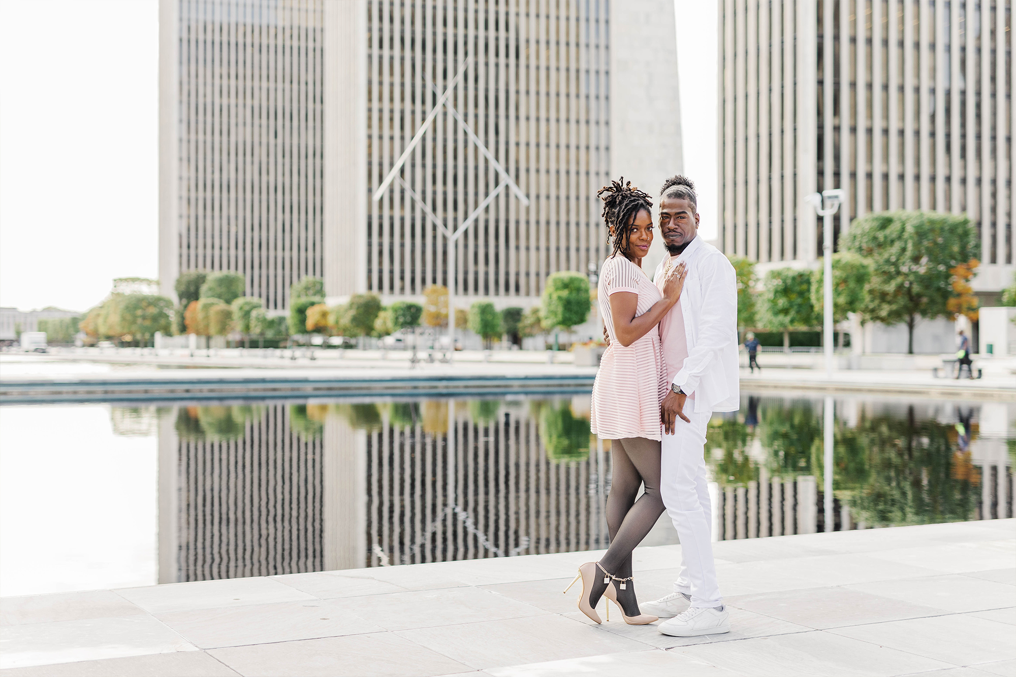 engaged couple during session in plaza complex with city buildings and water