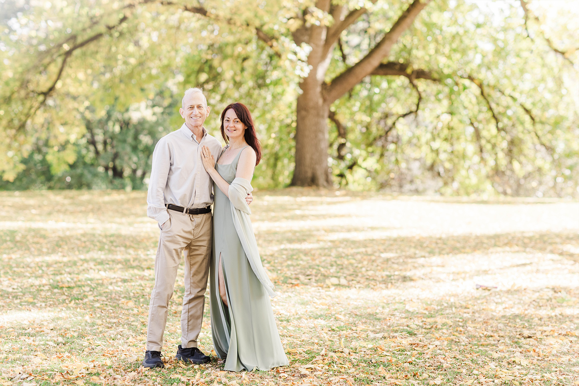 couple posing in front of large tree in park