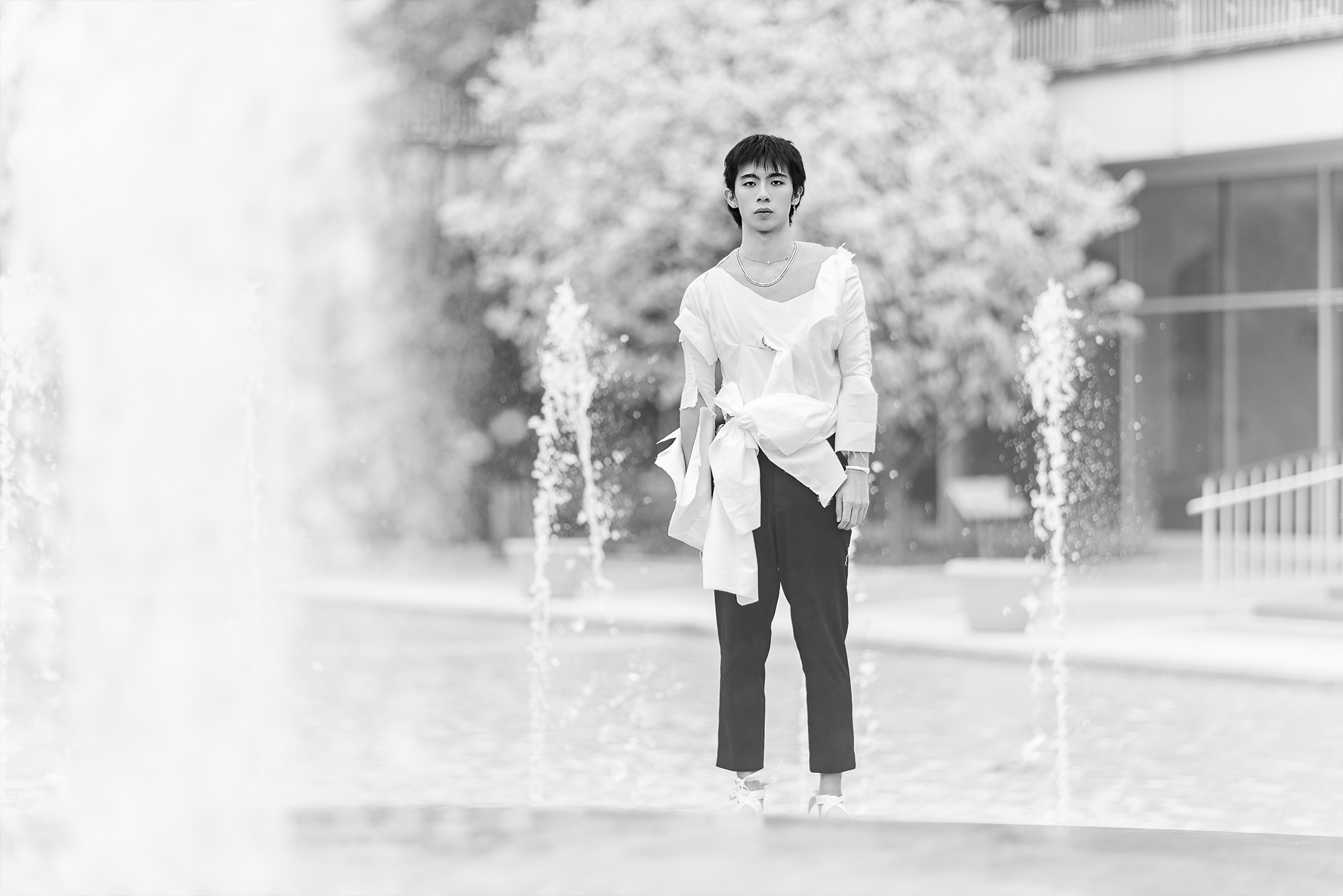 man with ripped clothing standing on top of bench with water fountains