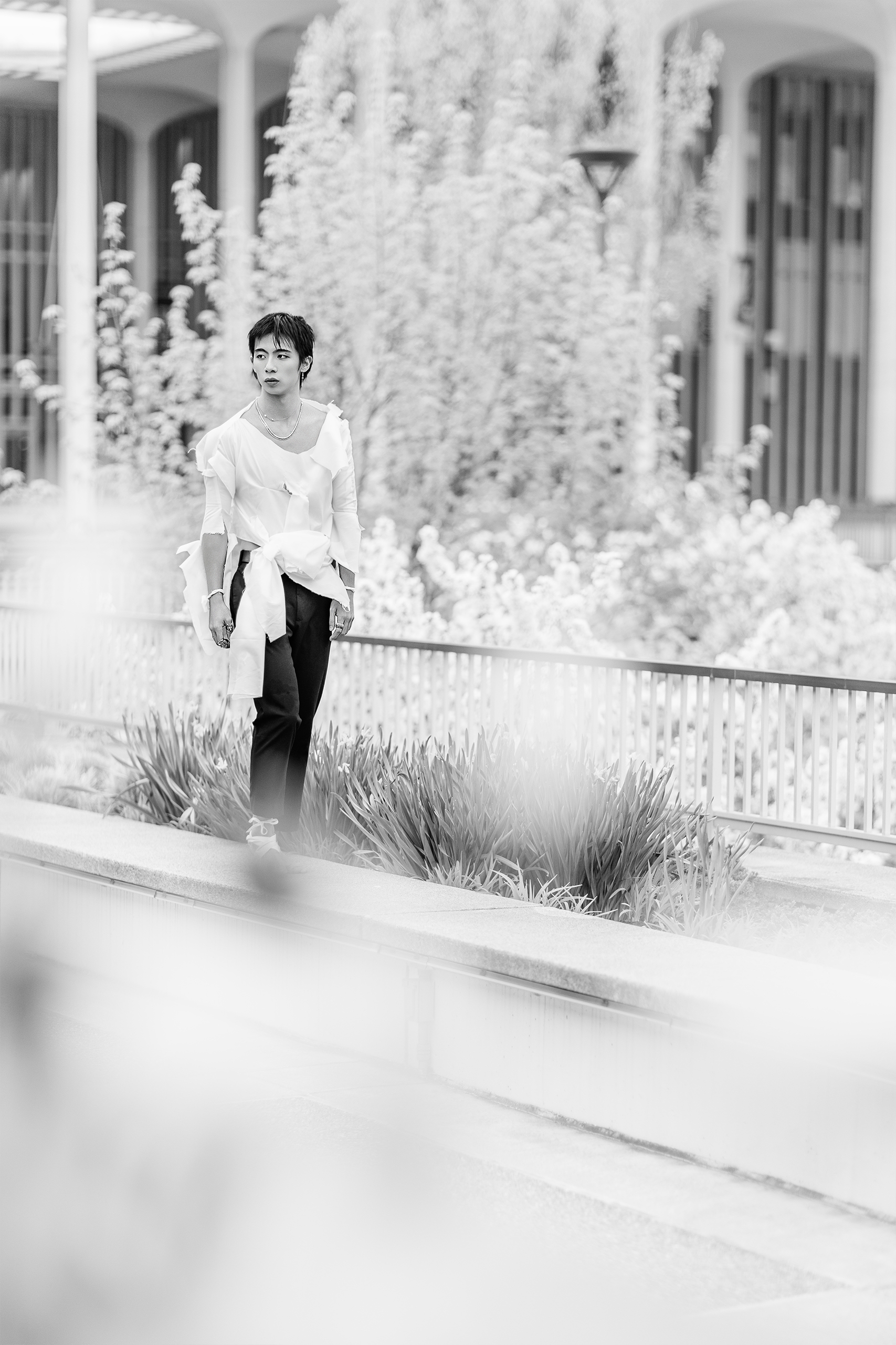 man walking on ledge with torn clothing in front of school campus