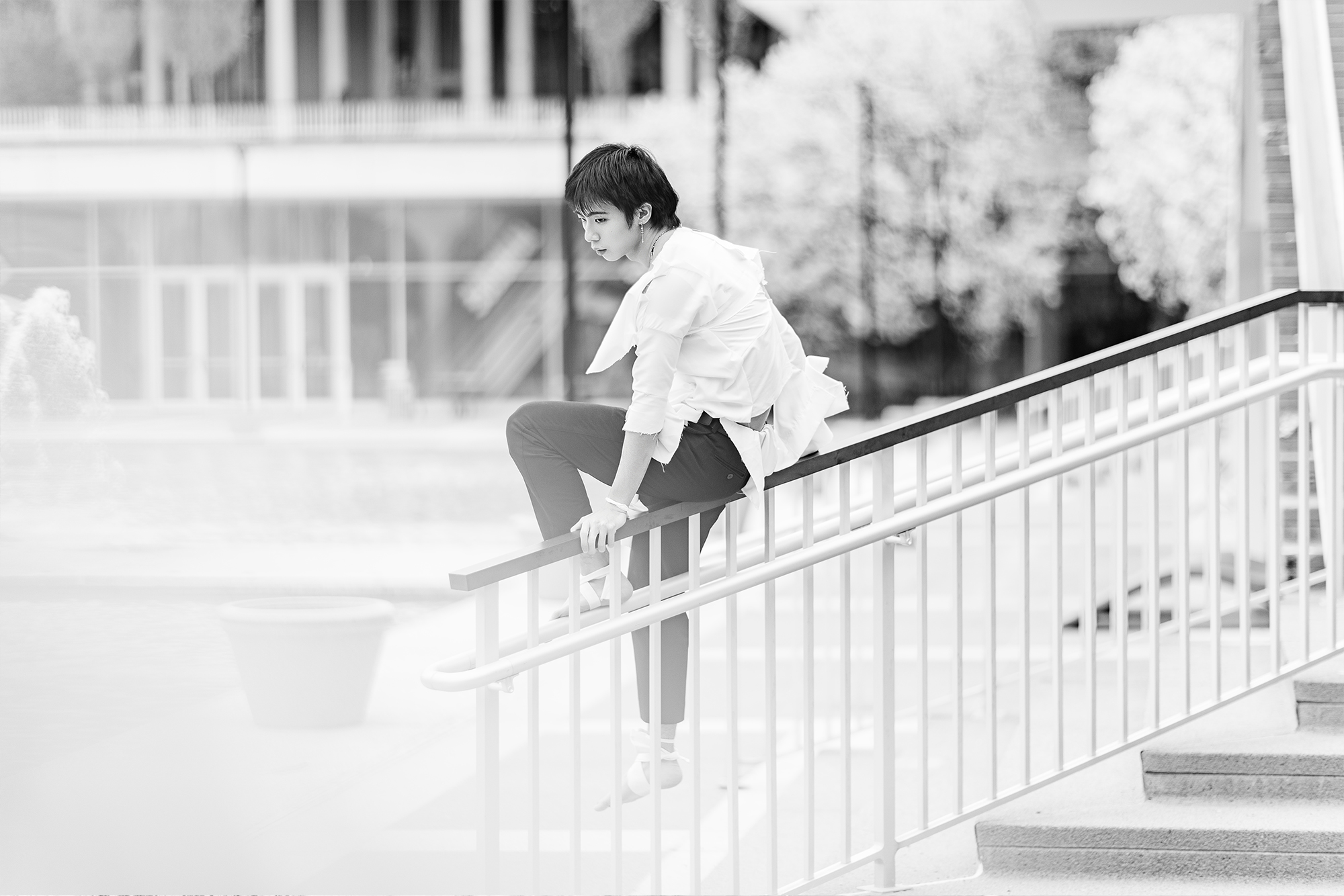 man sitting on railing with torn clothing in front of campus