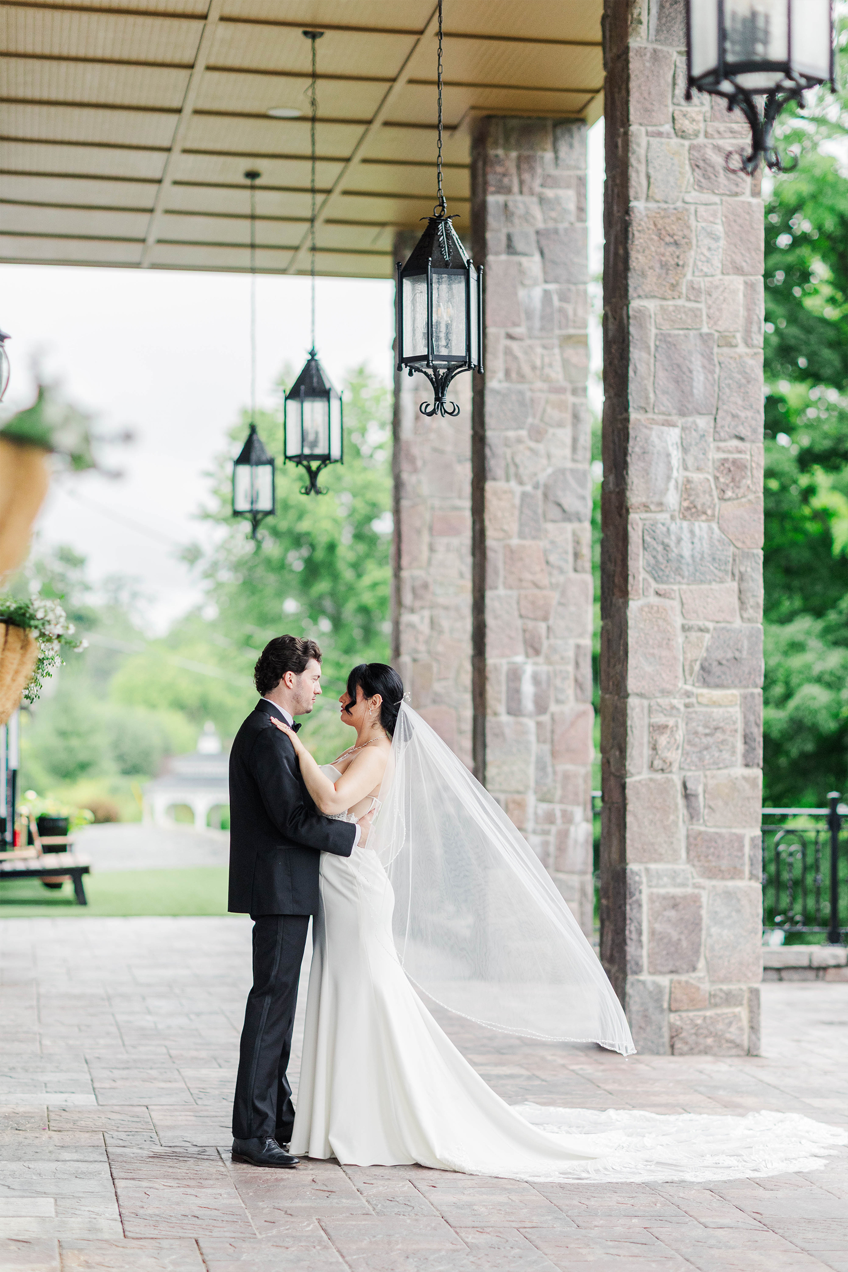 bride and groom sharing a moment on outdoor patio with flying wedding veil