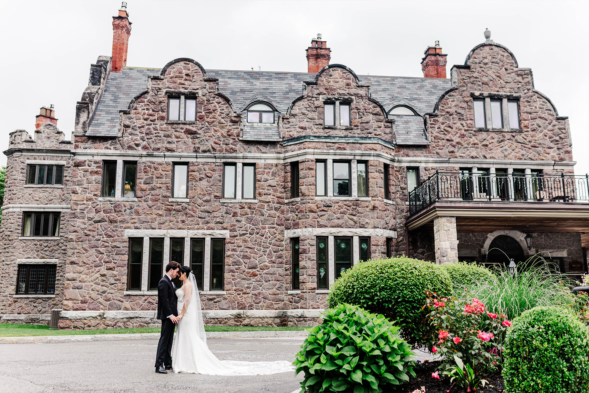 bride and groom posing in front of wedding venue with castle-like architecture