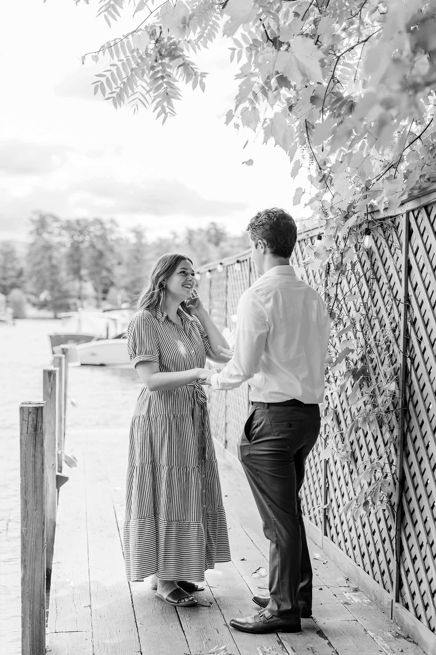 boyfriend proposing to girlfriend on lake dock with greenery