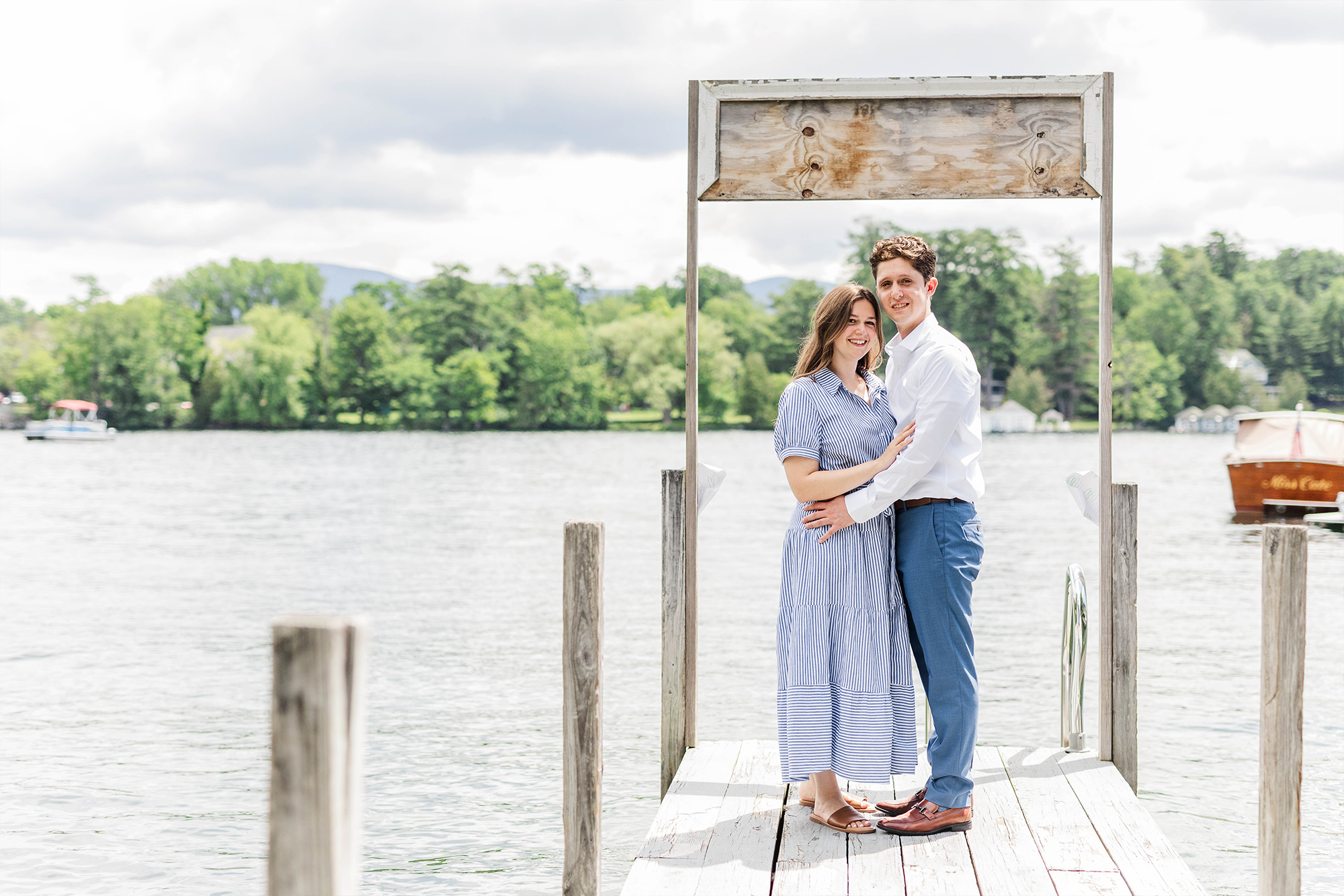 engaged couple posing with each other on dock with lake drop view with boat