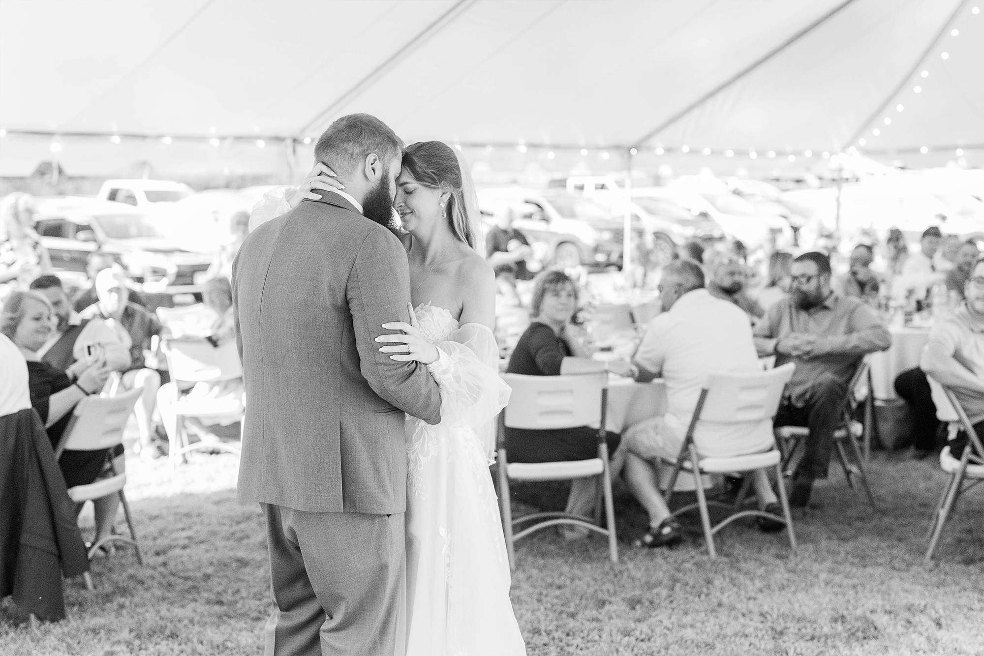 married couple during first dance in reception tent with guests